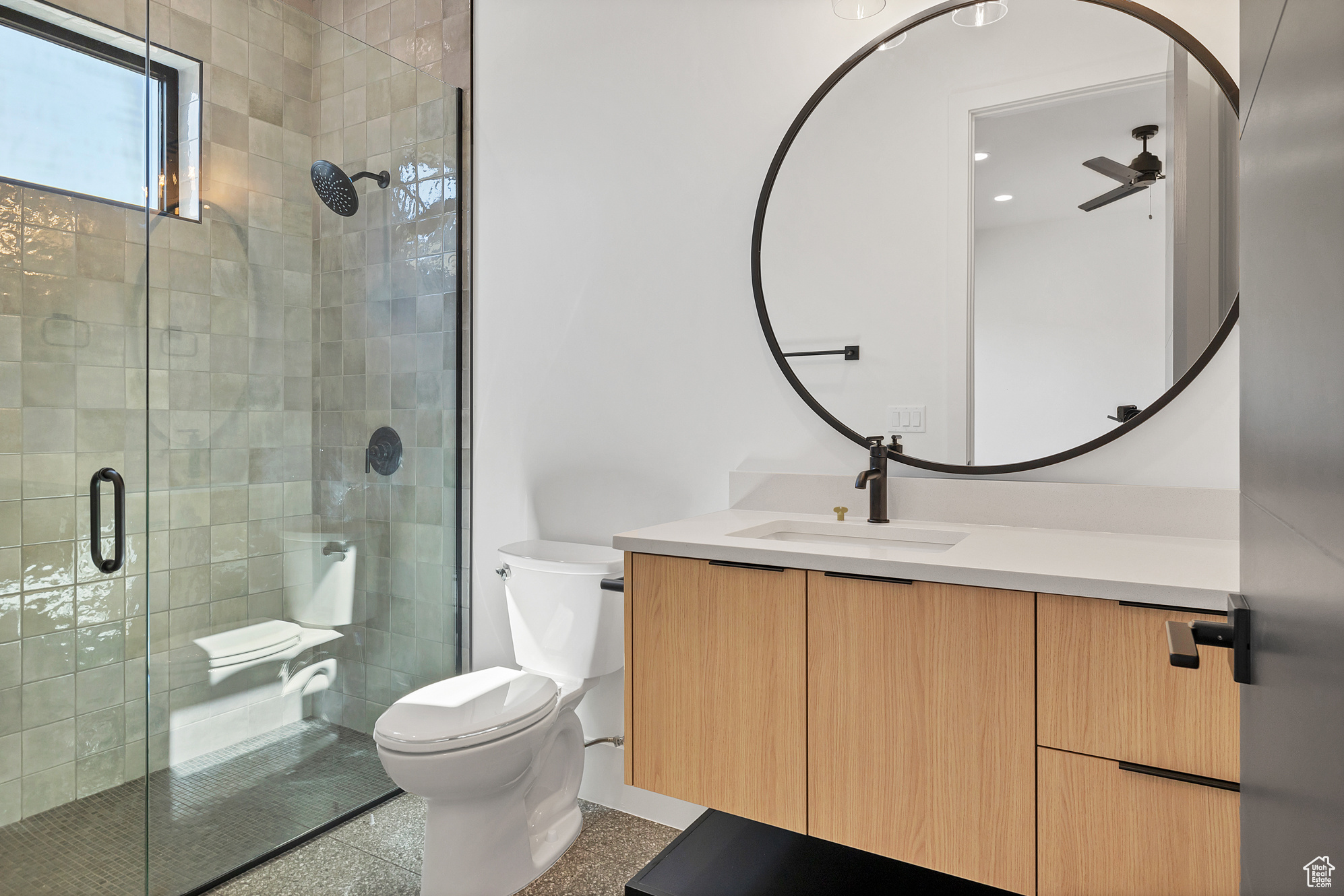 Bathroom featuring a shower with door, tile patterned flooring, toilet, vanity, and ceiling fan