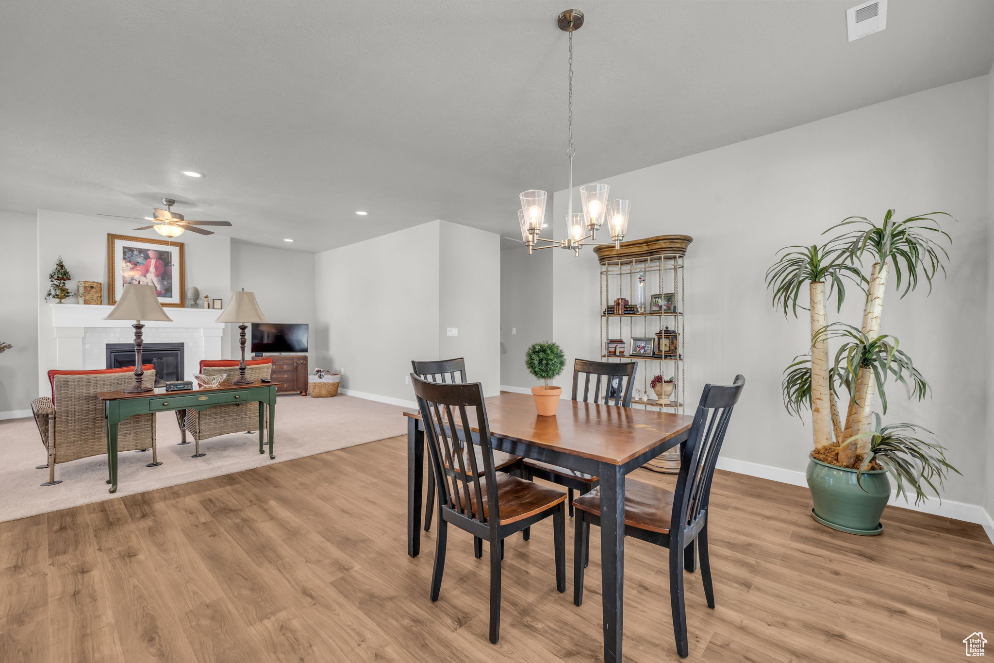 Dining room featuring a tile fireplace, ceiling fan with notable chandelier, and light hardwood / wood-style flooring