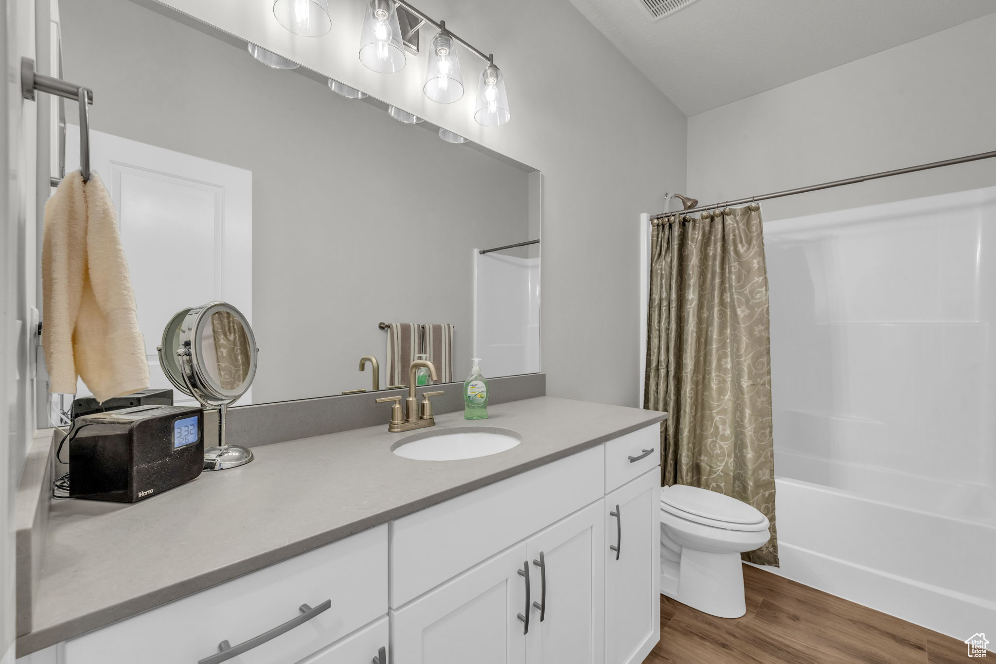 Full bathroom featuring shower / tub combo with curtain, vanity, wood-type flooring, and toilet