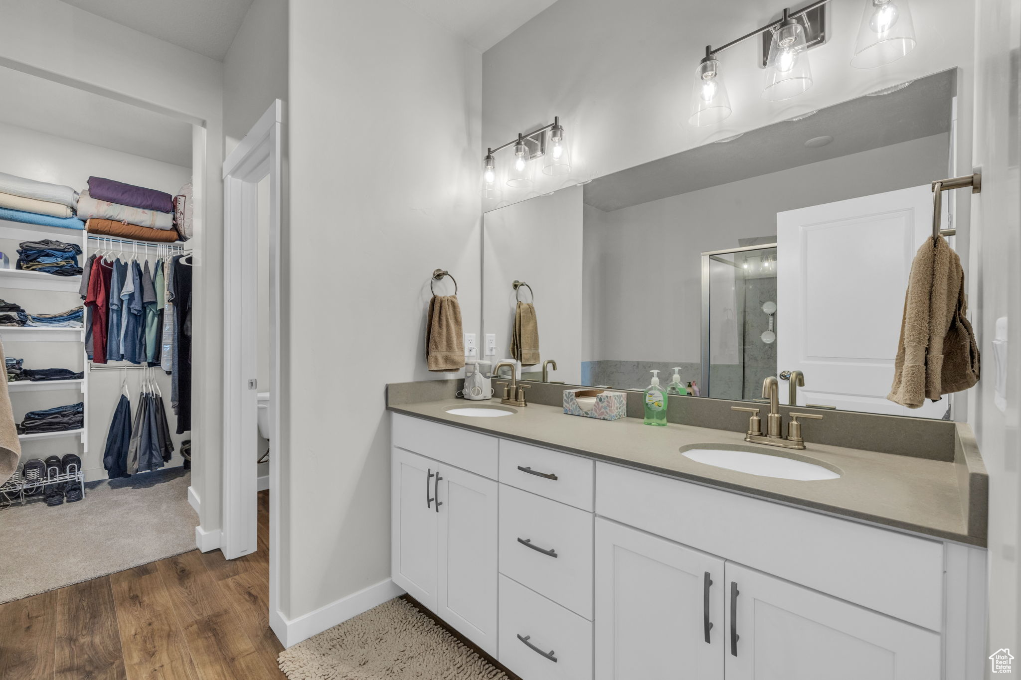 Bathroom with hardwood / wood-style floors, an enclosed shower, and dual bowl vanity