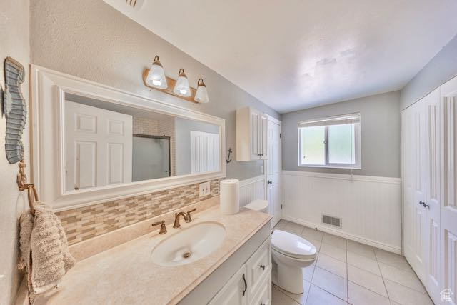 Bathroom featuring vanity, tile patterned flooring, toilet, and backsplash