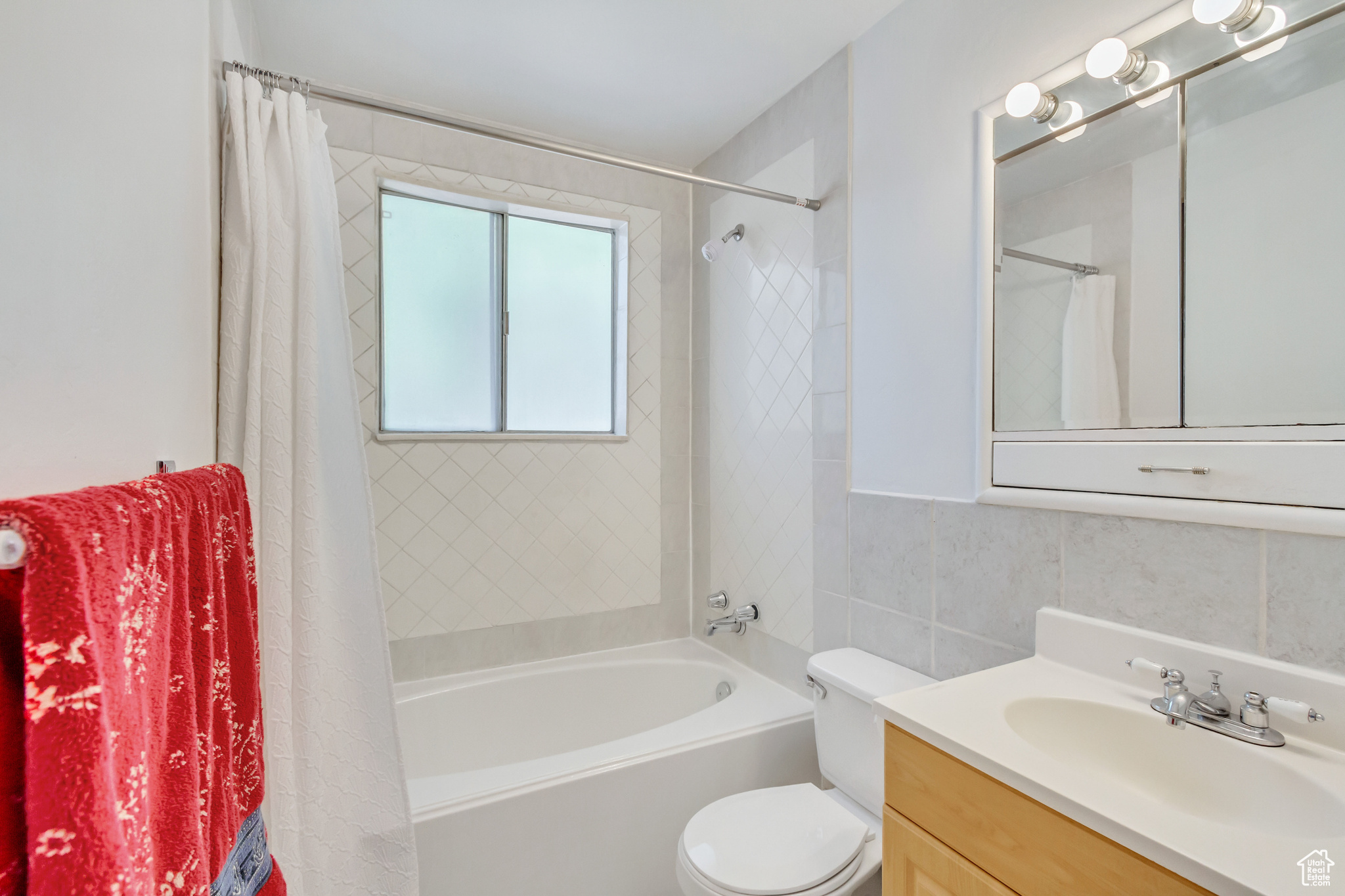 Full bathroom with vanity, tile walls, toilet, and shower / bath combination with curtain