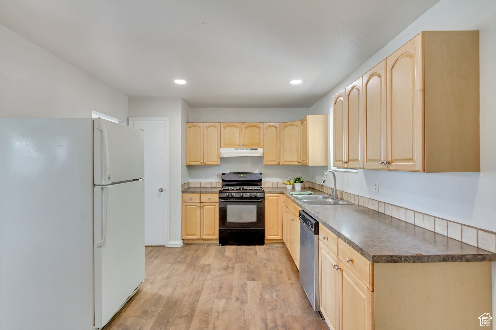 Kitchen with white refrigerator, sink, gas stove, light wood-type flooring, and maple cabinetry