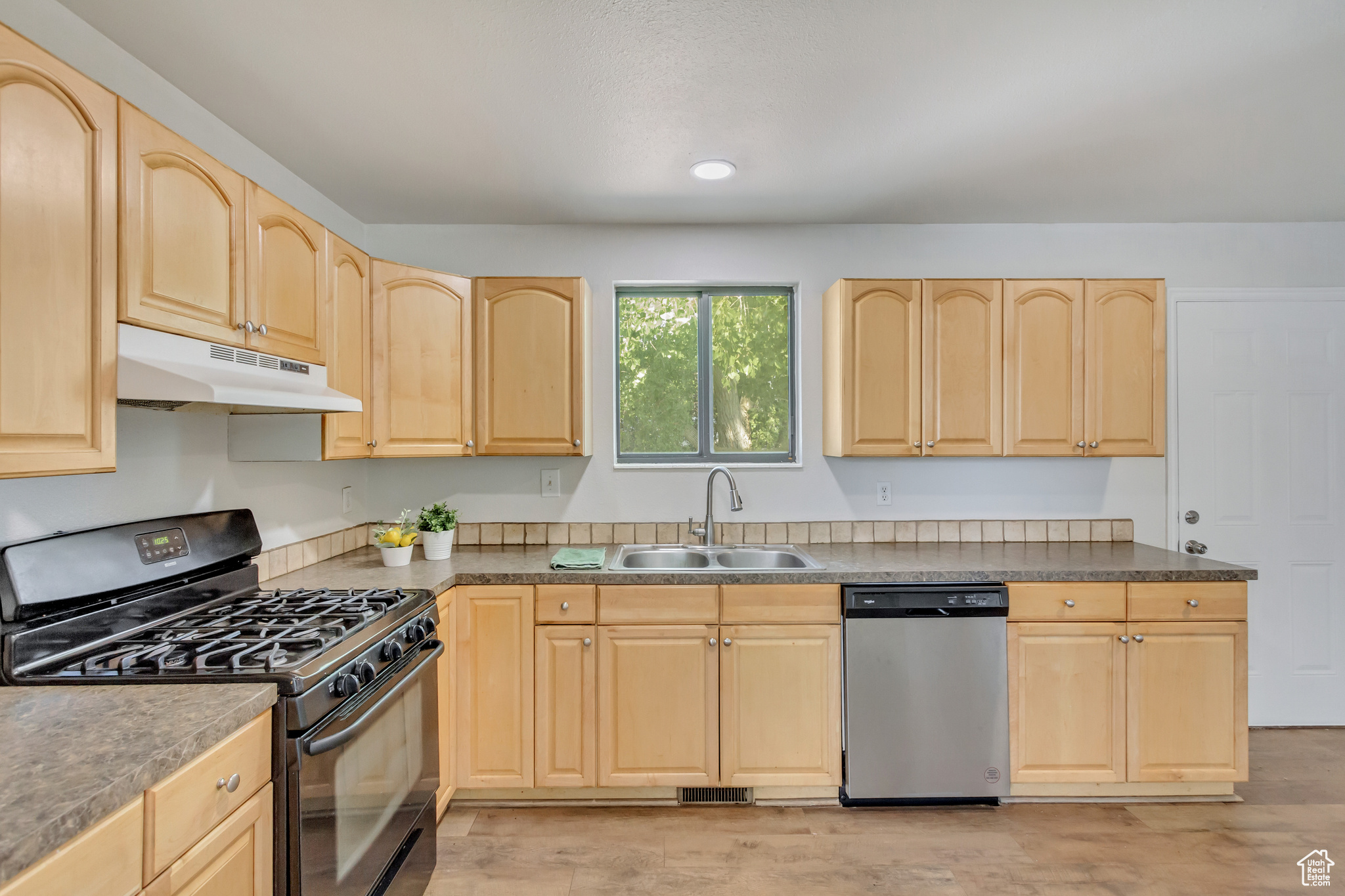 Kitchen with maple cabinetry, dishwasher, light hardwood / wood-style flooring, and black gas stove