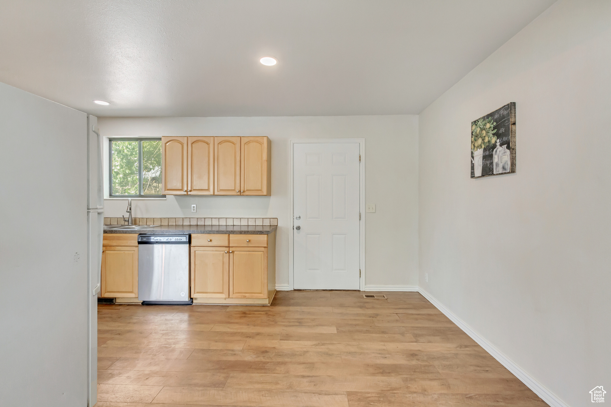 dining area off the kitchen with light hardwood / wood-style floors, sink, dishwasher, and maple cabinets