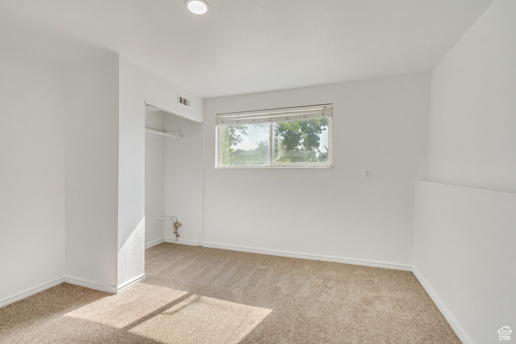 Bedroom with light carpet and a closet