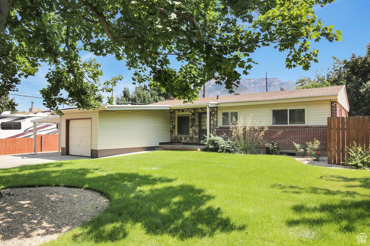 Single story home featuring a garage and a front yard