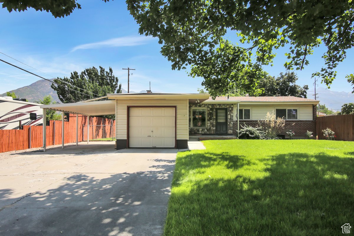 Single story home featuring a garage and a front yard