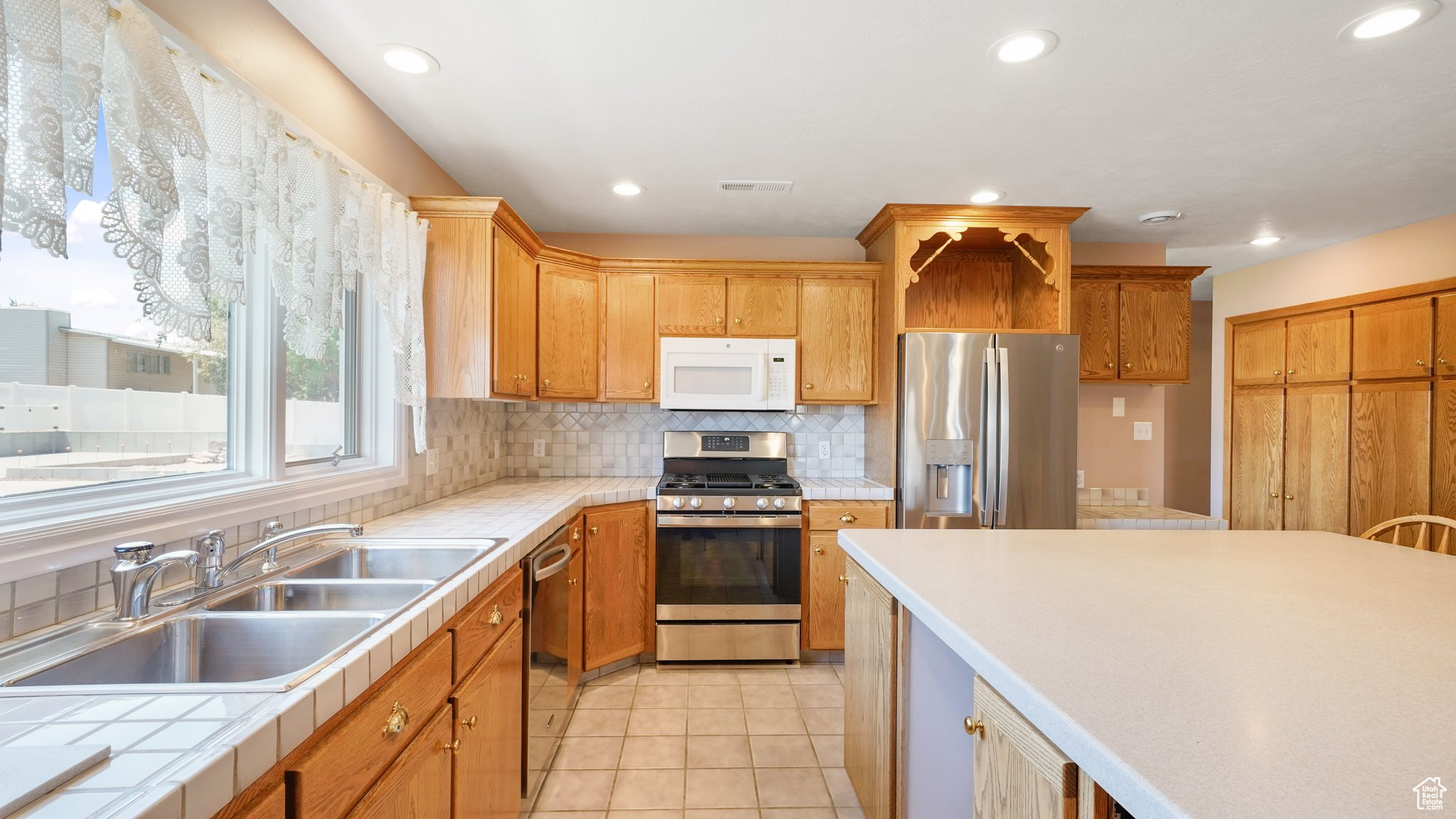 Kitchen with appliances with stainless steel finishes, tasteful backsplash, light tile patterned floors, and sink