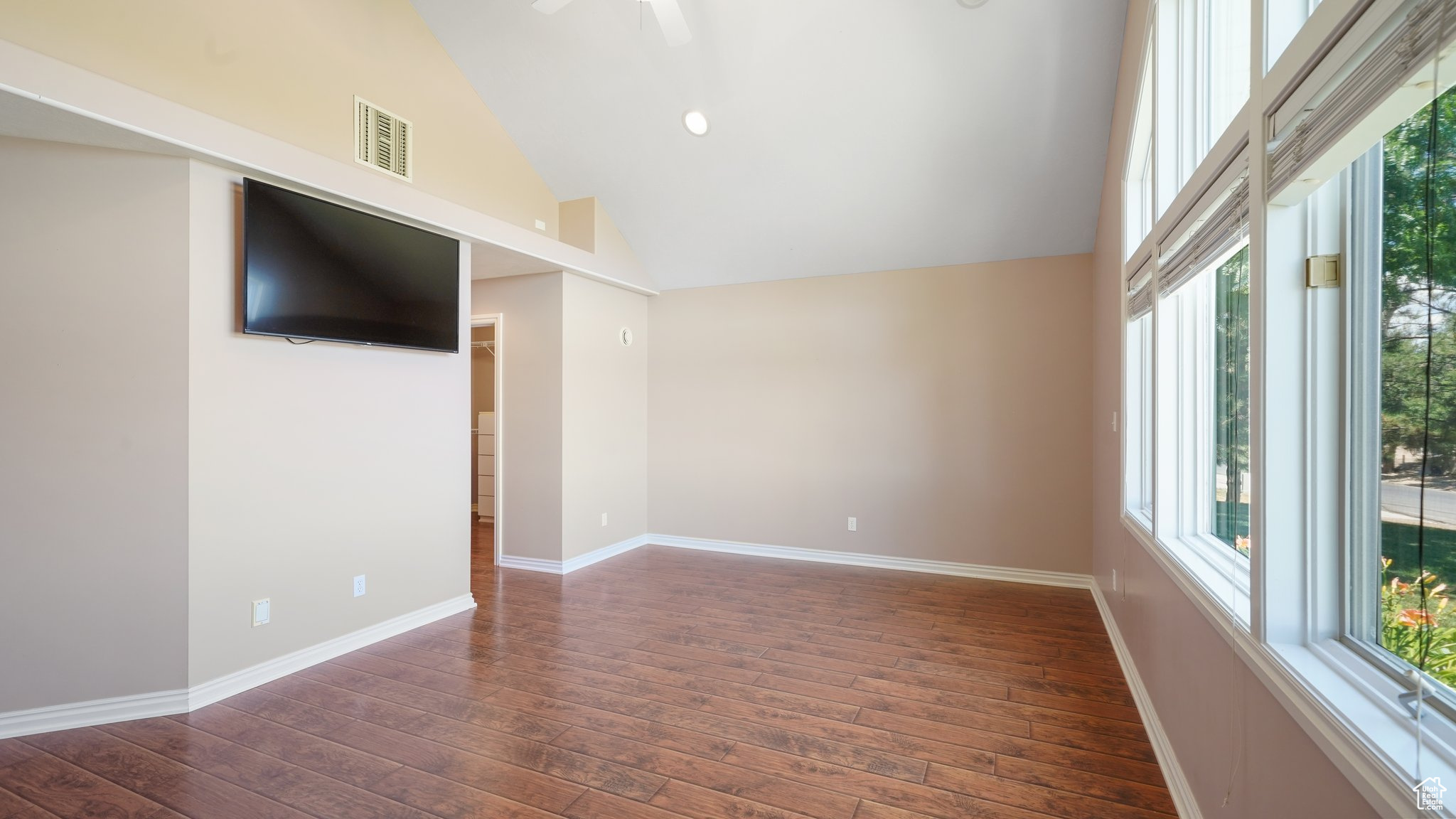 Interior space with dark hardwood / wood-style flooring, ceiling fan, and high vaulted ceiling