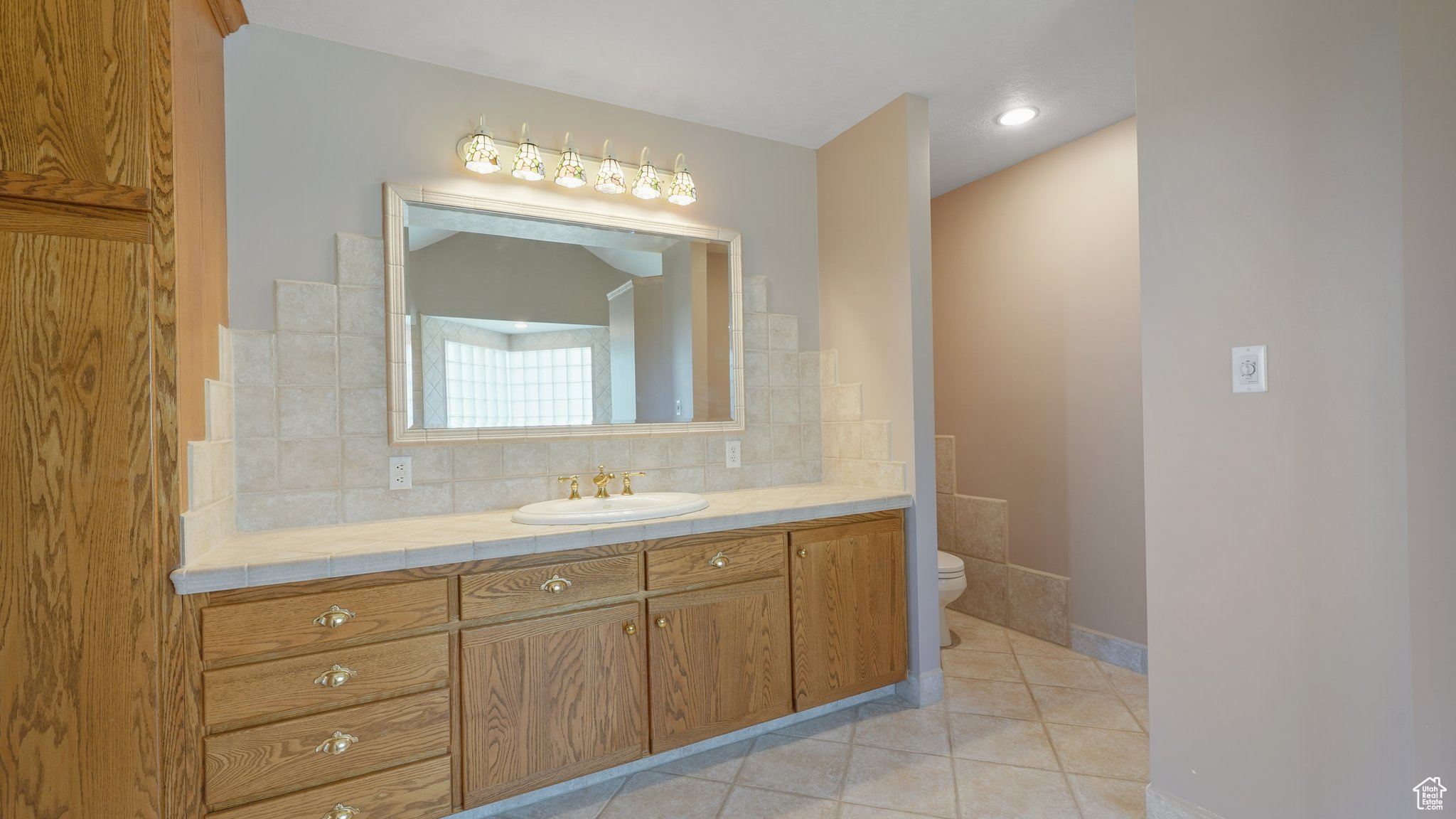 Bathroom featuring tile walls, tile patterned floors, toilet, and vanity