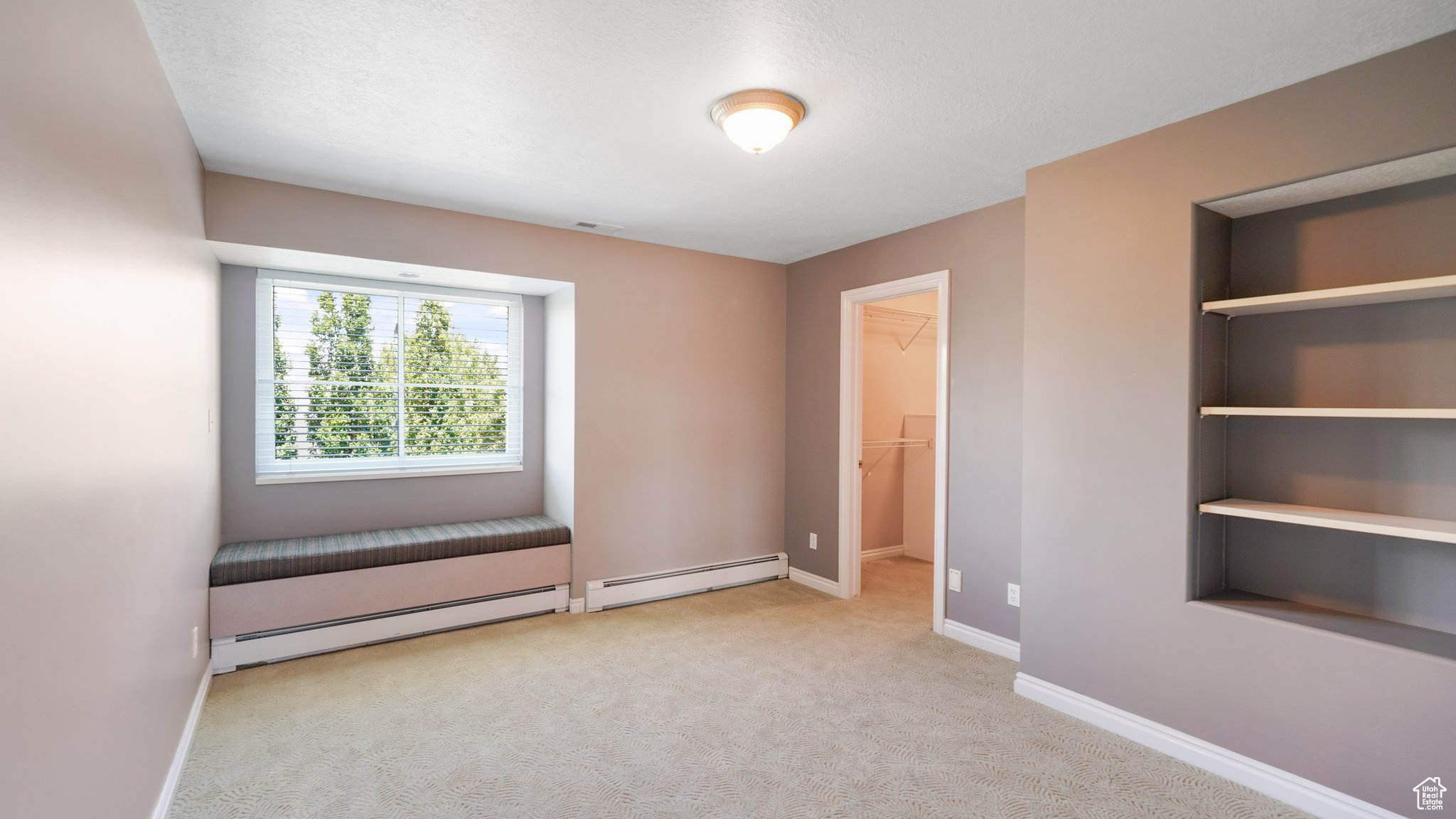 Carpeted empty room with a baseboard heating unit