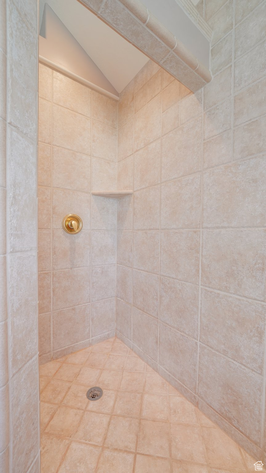 Bathroom with tiled shower and lofted ceiling