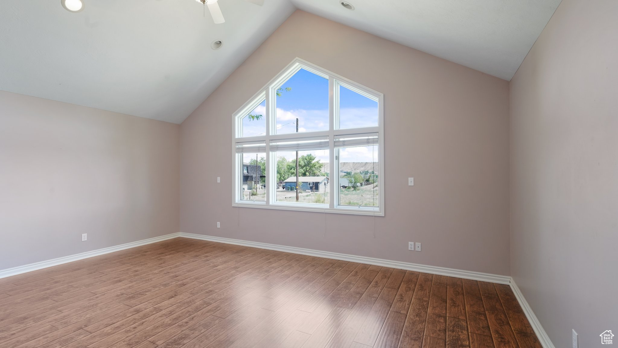 Primary bedroom with wood-type flooring, lofted ceiling, and ceiling fan