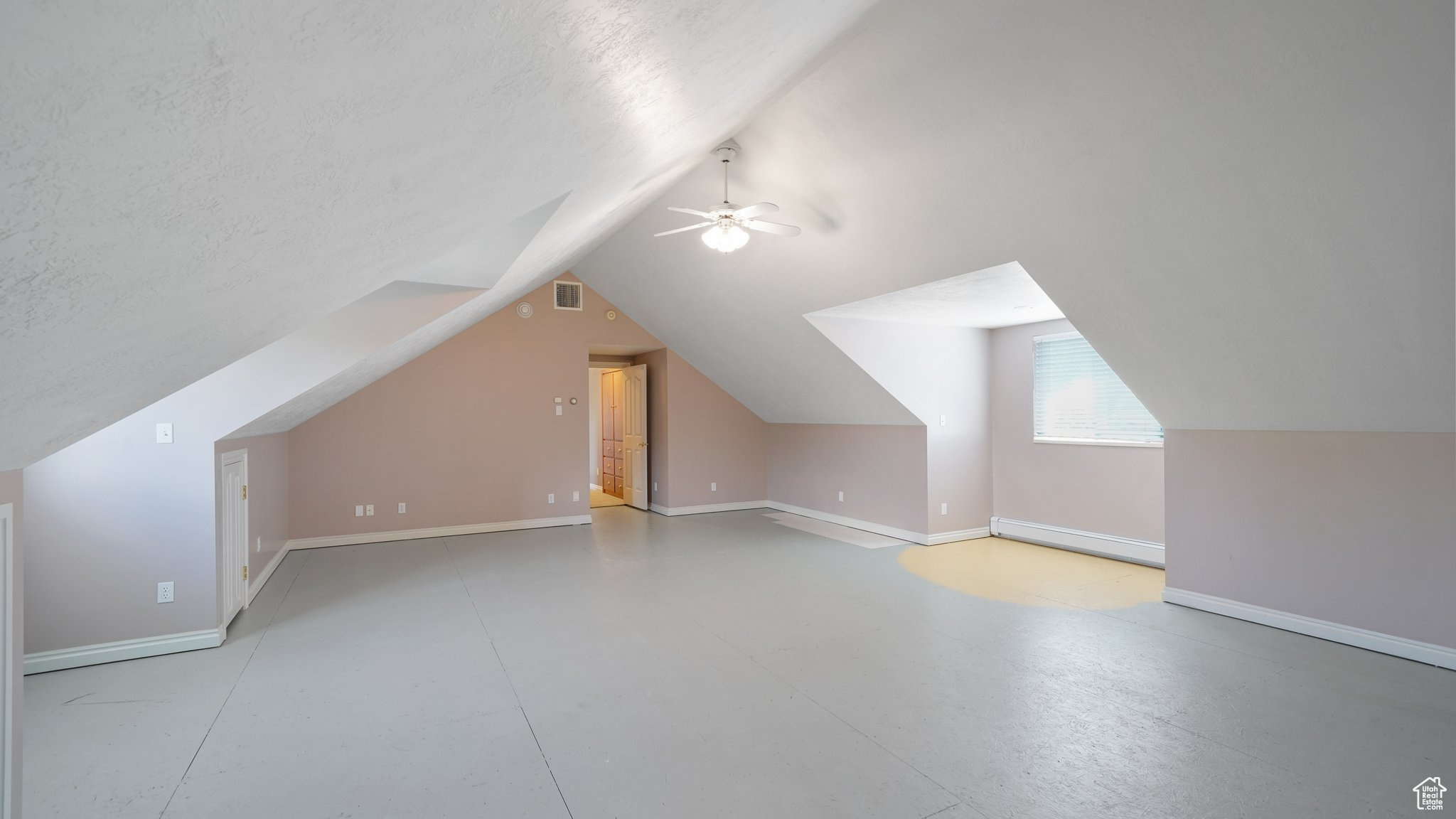 Additional living space featuring a textured ceiling, ceiling fan, lofted ceiling, and baseboard heating