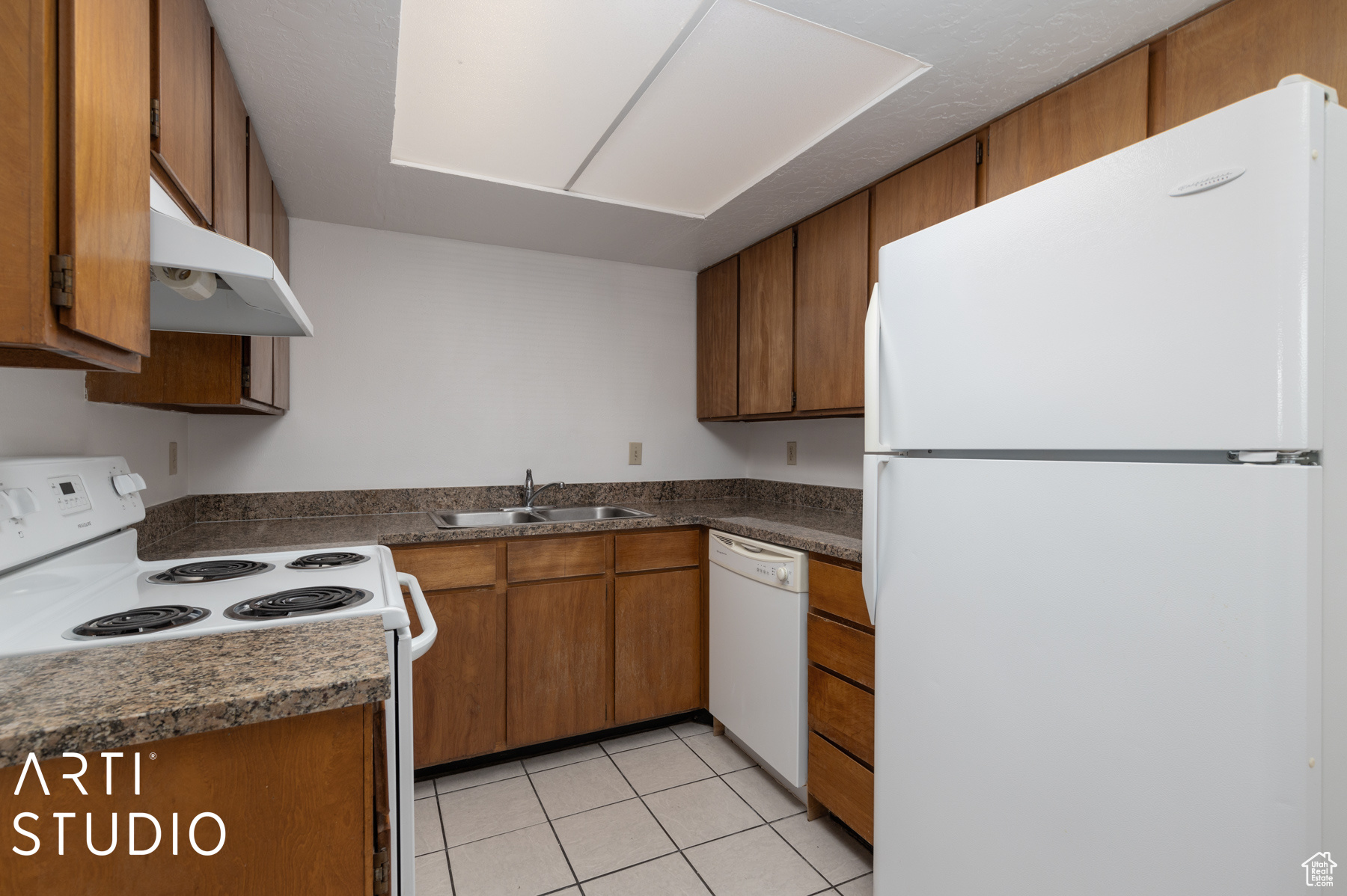 Kitchen with sink, wall chimney exhaust hood, light tile patterned floors, and white appliances