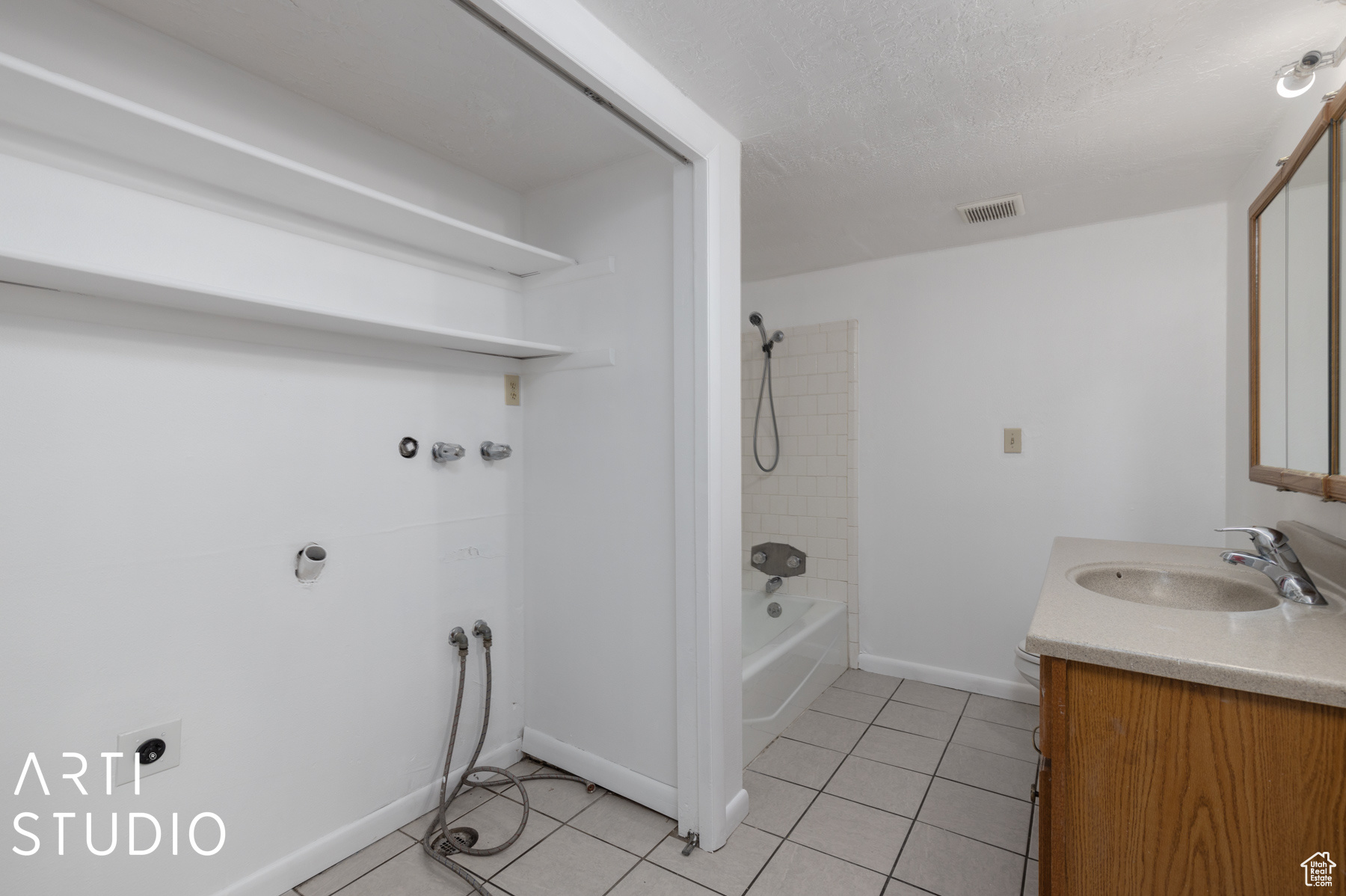 Bathroom featuring a textured ceiling, vanity, tiled shower / bath, and tile patterned flooring