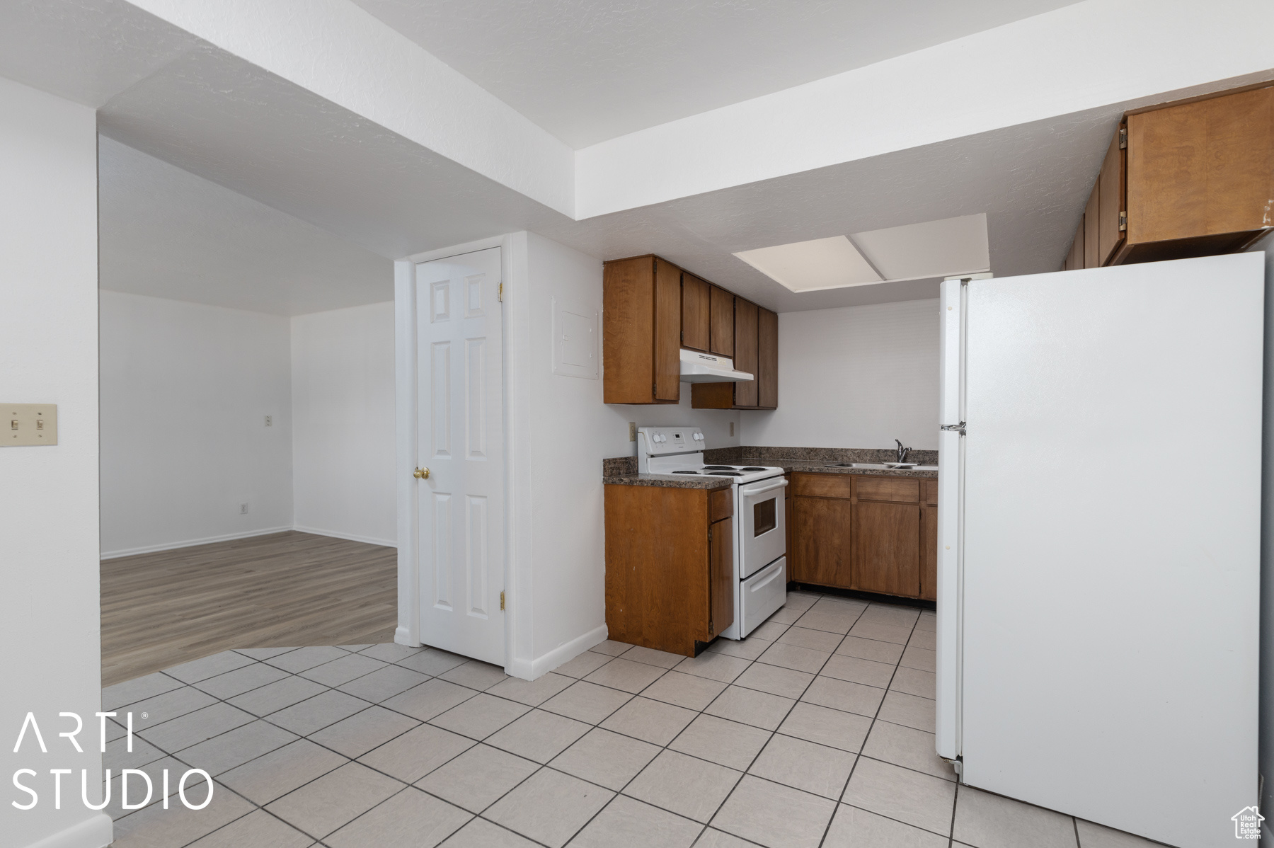 Kitchen with light hardwood / wood-style flooring, white appliances, and sink