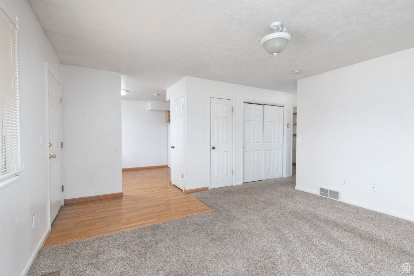 Unfurnished bedroom featuring light carpet and multiple closets