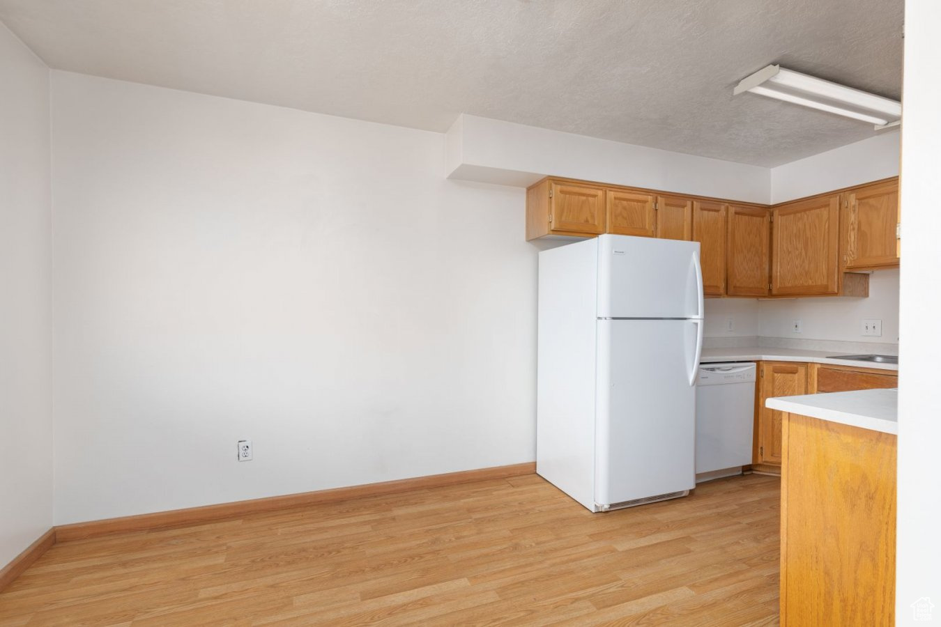 Kitchen featuring sink, light wood-type flooring, and white appliances