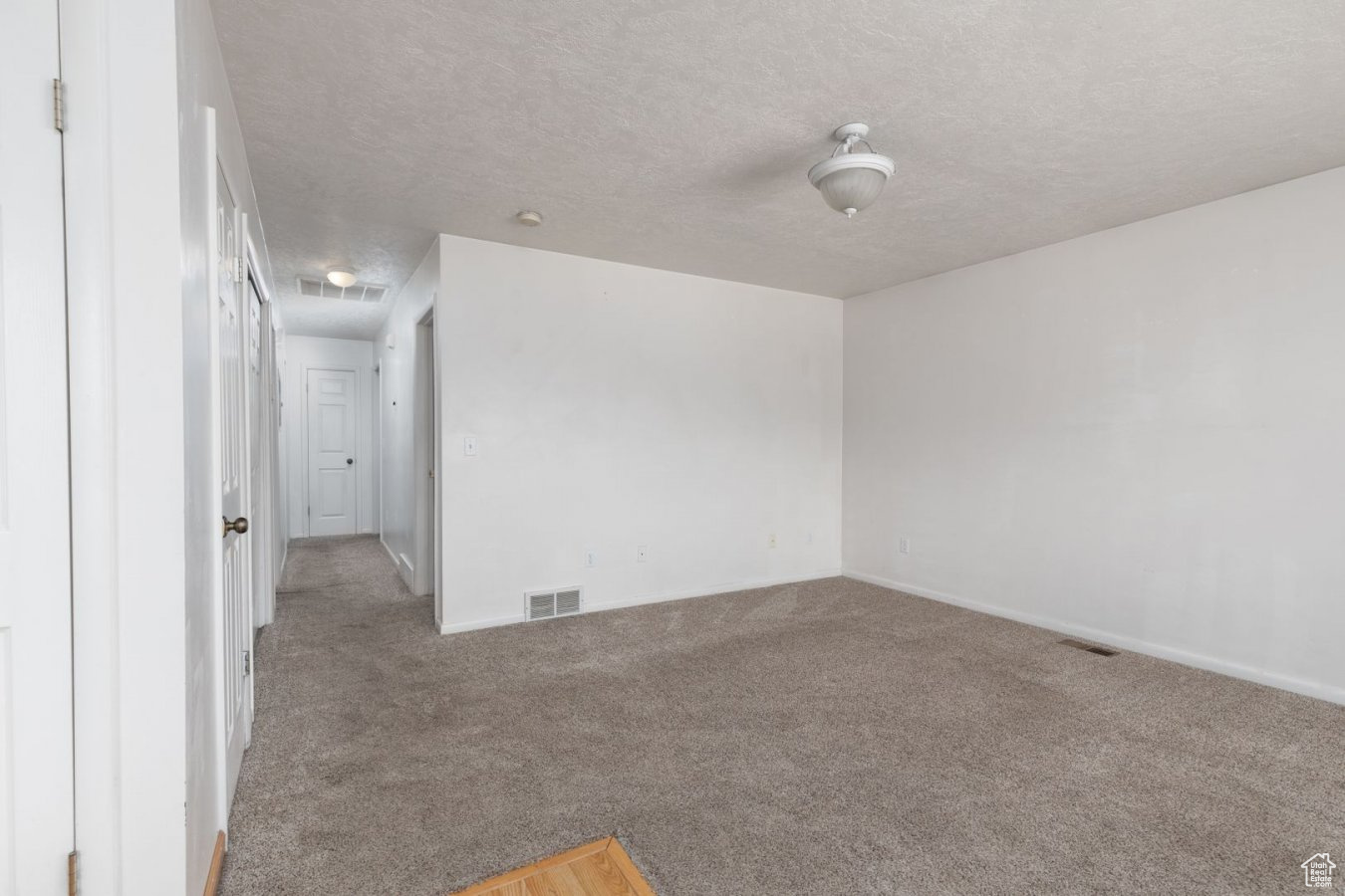 Carpeted spare room featuring a textured ceiling