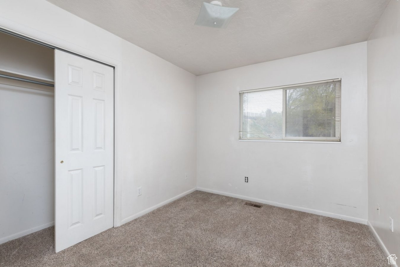 Unfurnished bedroom with light colored carpet and a closet