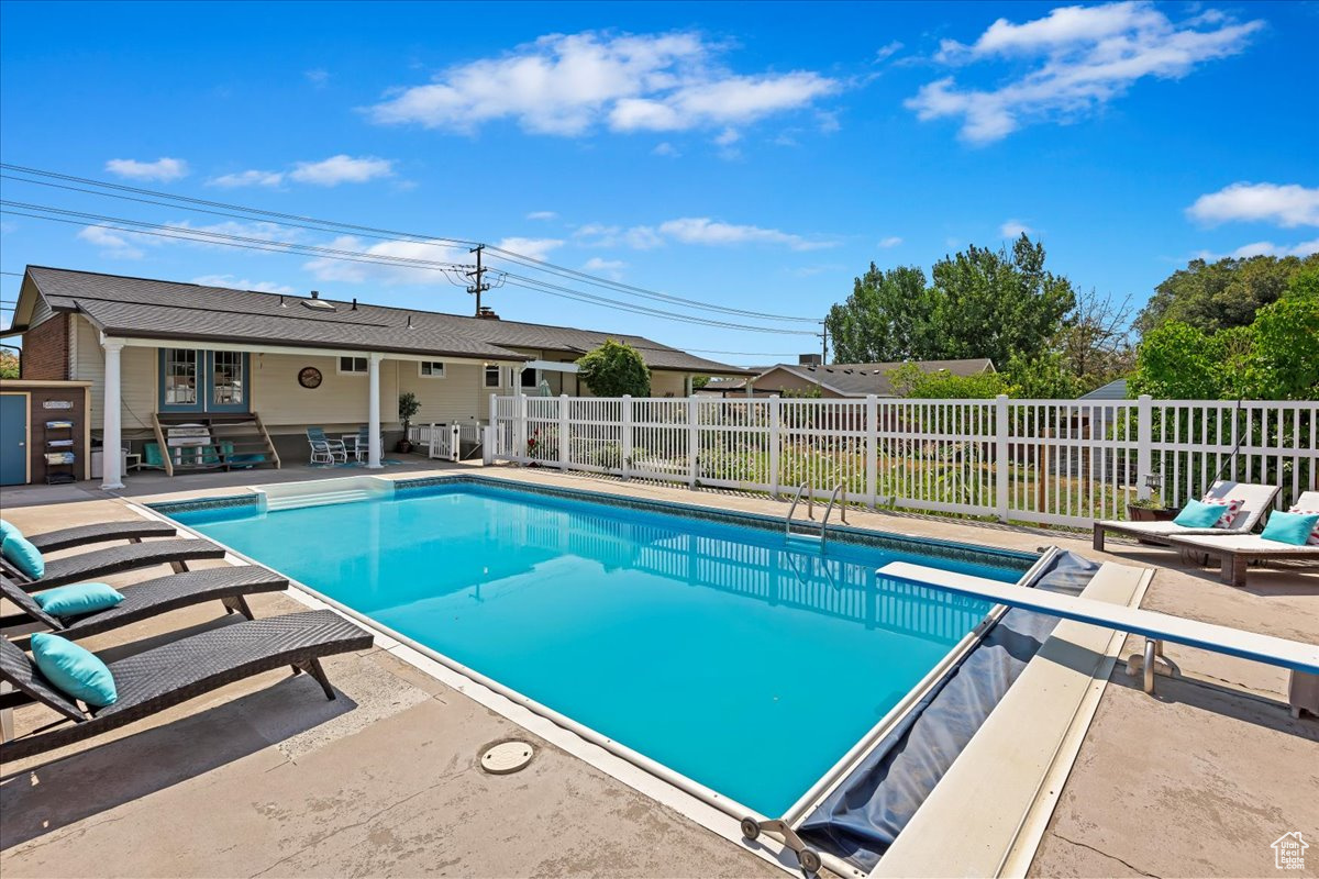 View of pool with a diving board and a patio