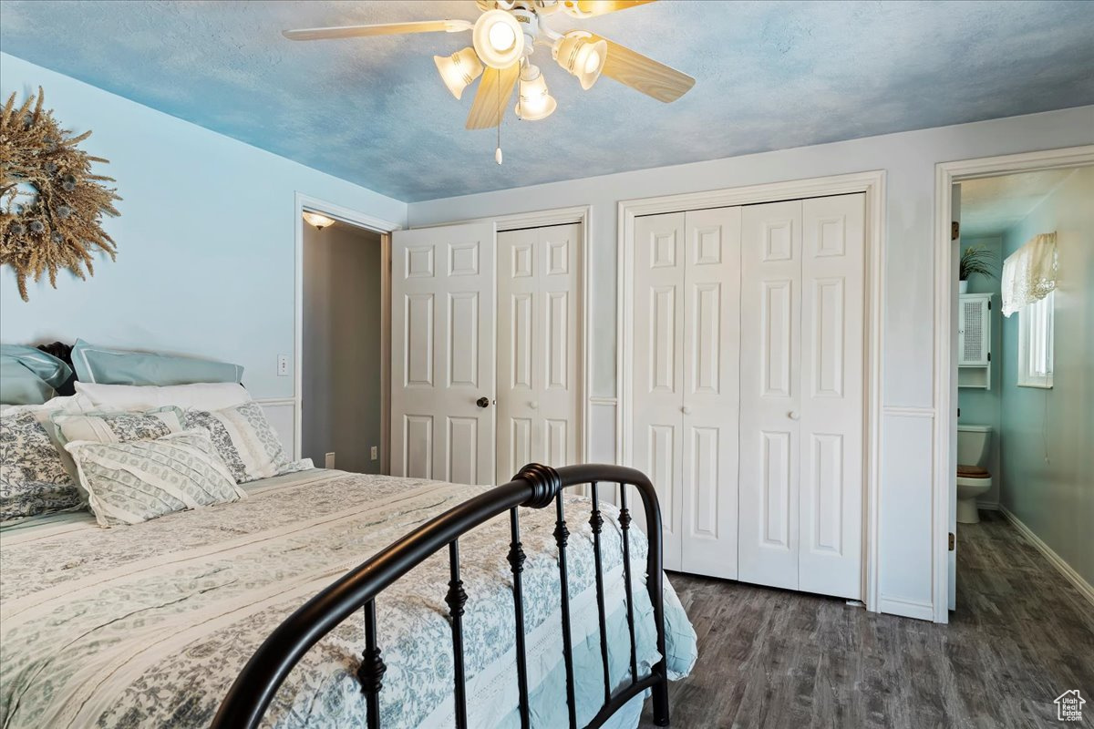 Bedroom featuring multiple closets, dark wood-type flooring, ceiling fan, and connected bathroom