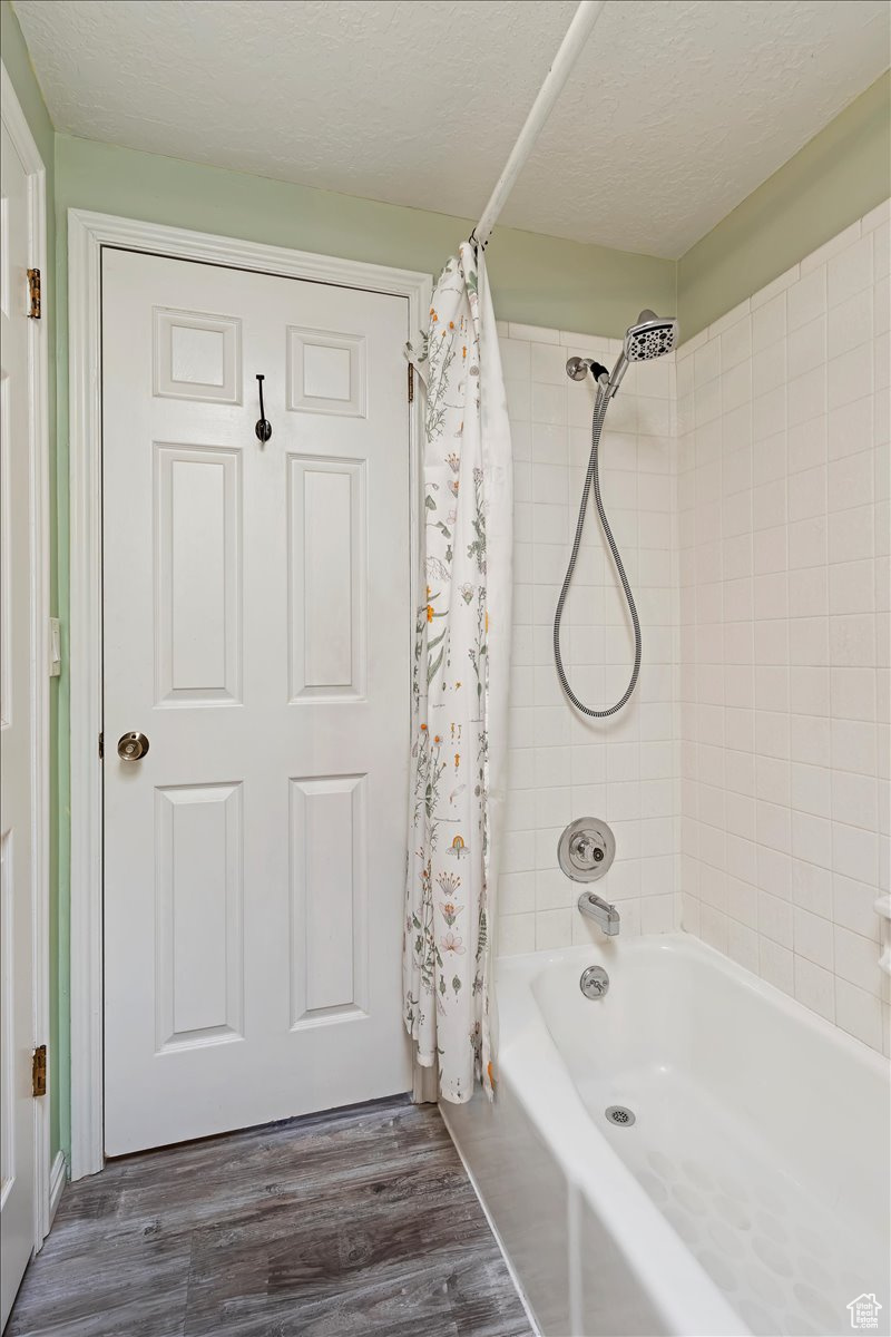 Bathroom featuring shower / bath combo, a textured ceiling, and hardwood / wood-style floors