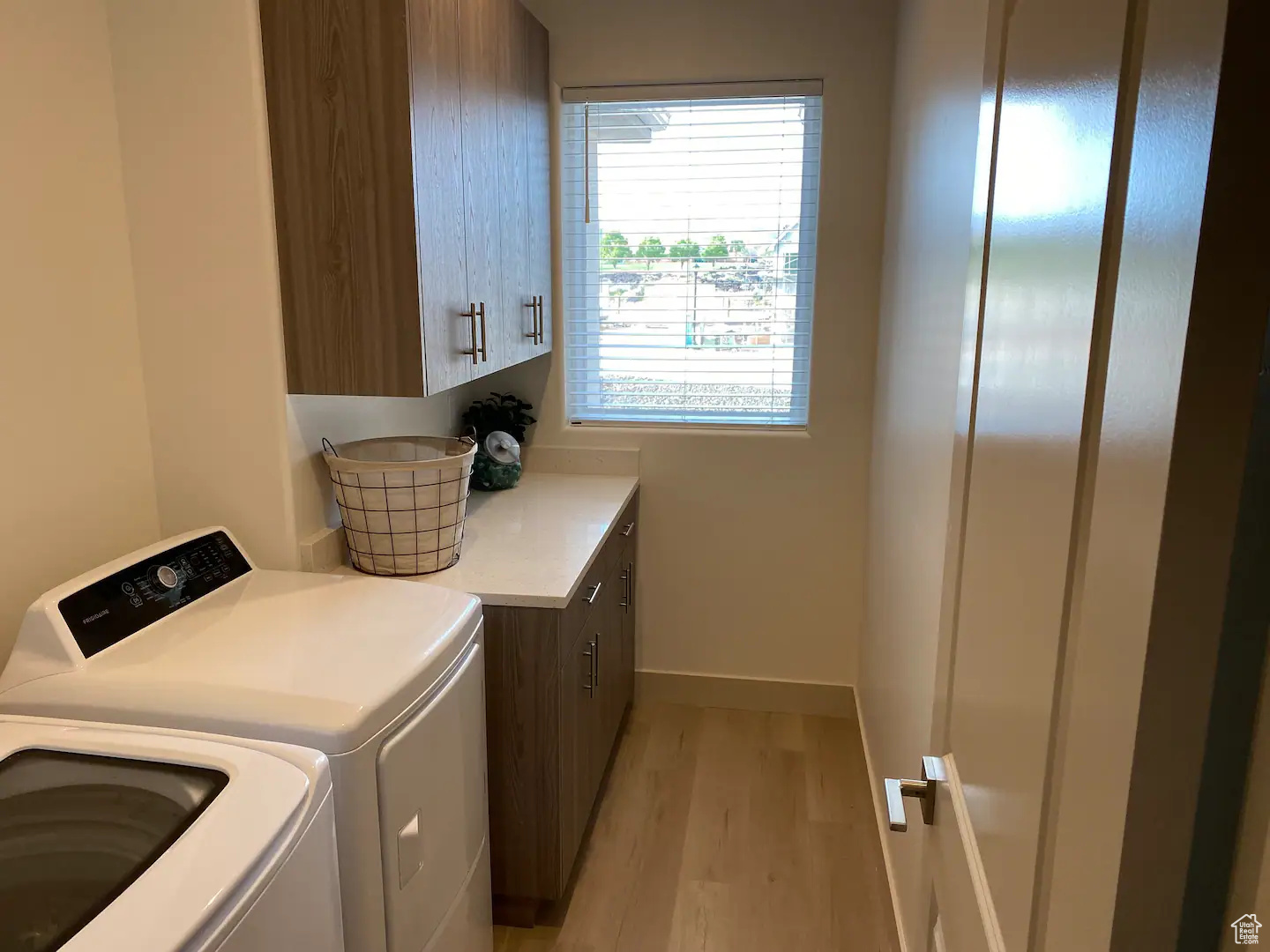 Washroom with cabinets, washer and dryer, and light hardwood / wood-style flooring