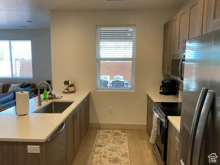 Kitchen with sink, light hardwood / wood-style flooring, kitchen peninsula, and stainless steel appliances