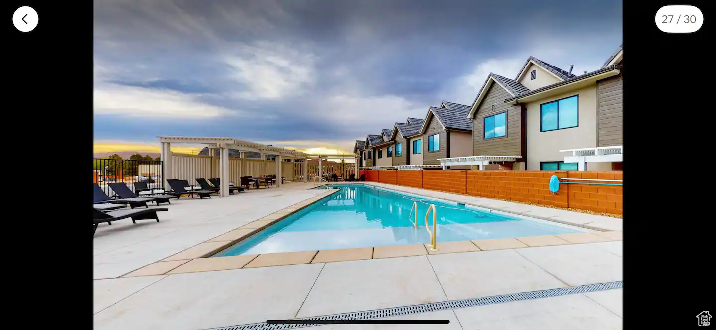 Pool at dusk featuring a patio area and a pergola