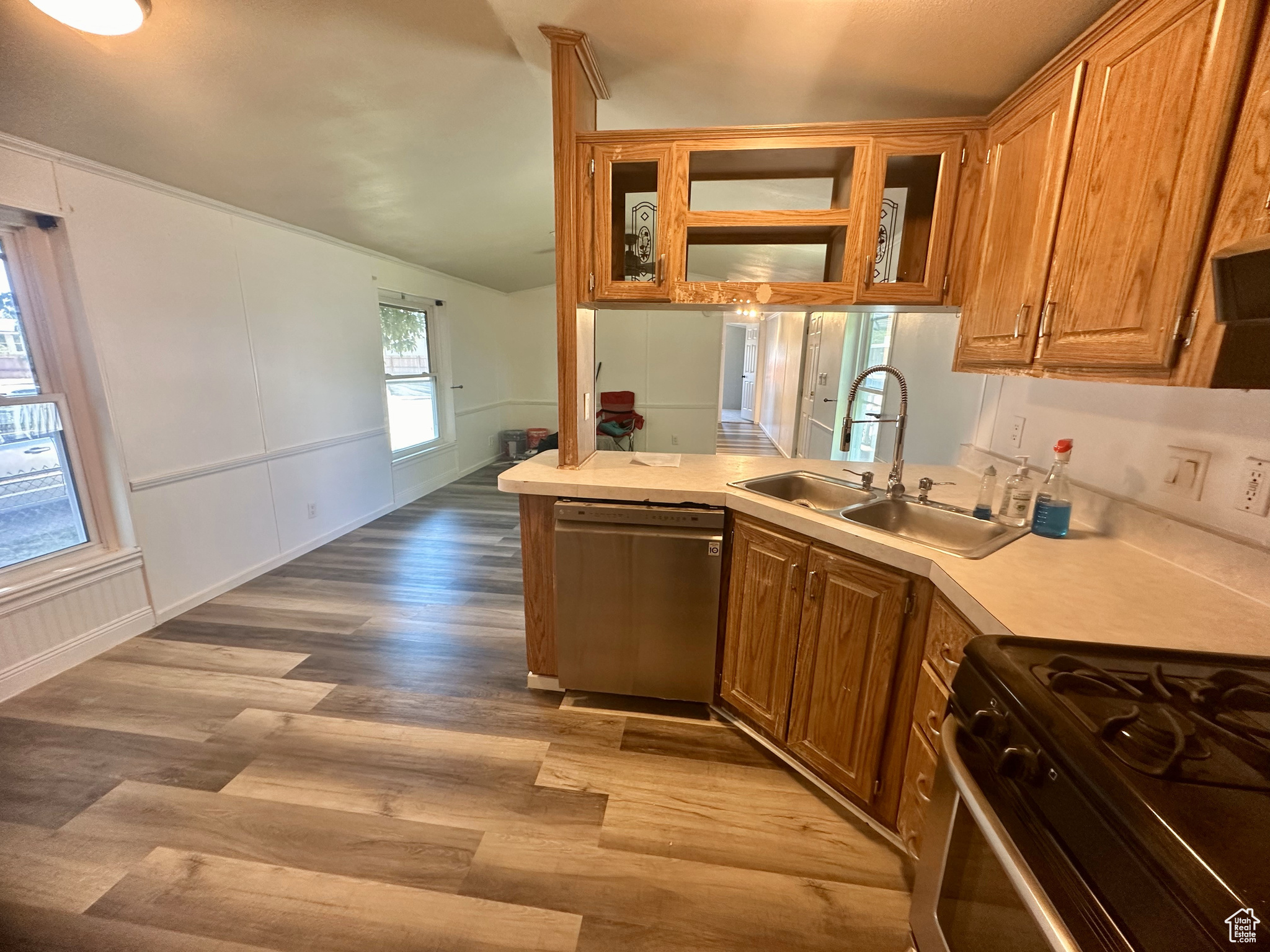 Kitchen featuring sink, dishwasher, stove, light hardwood / wood-style flooring, and kitchen peninsula