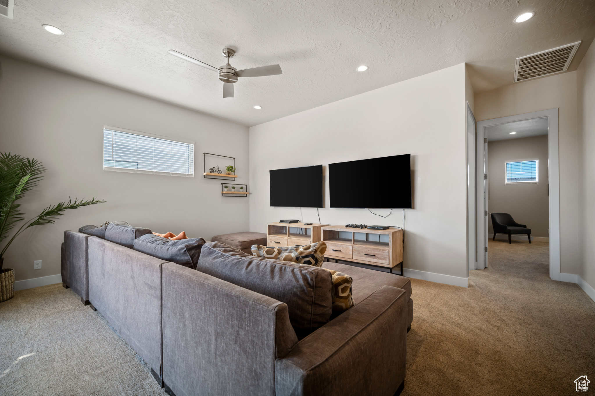 Living room with a textured ceiling, carpet floors, and ceiling fan