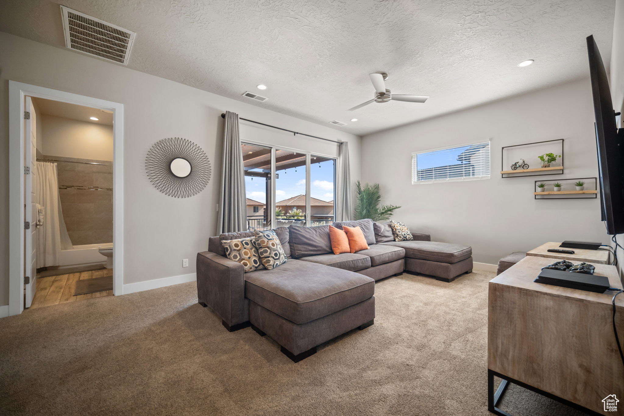 Living room featuring ceiling fan, a textured ceiling, and light carpet