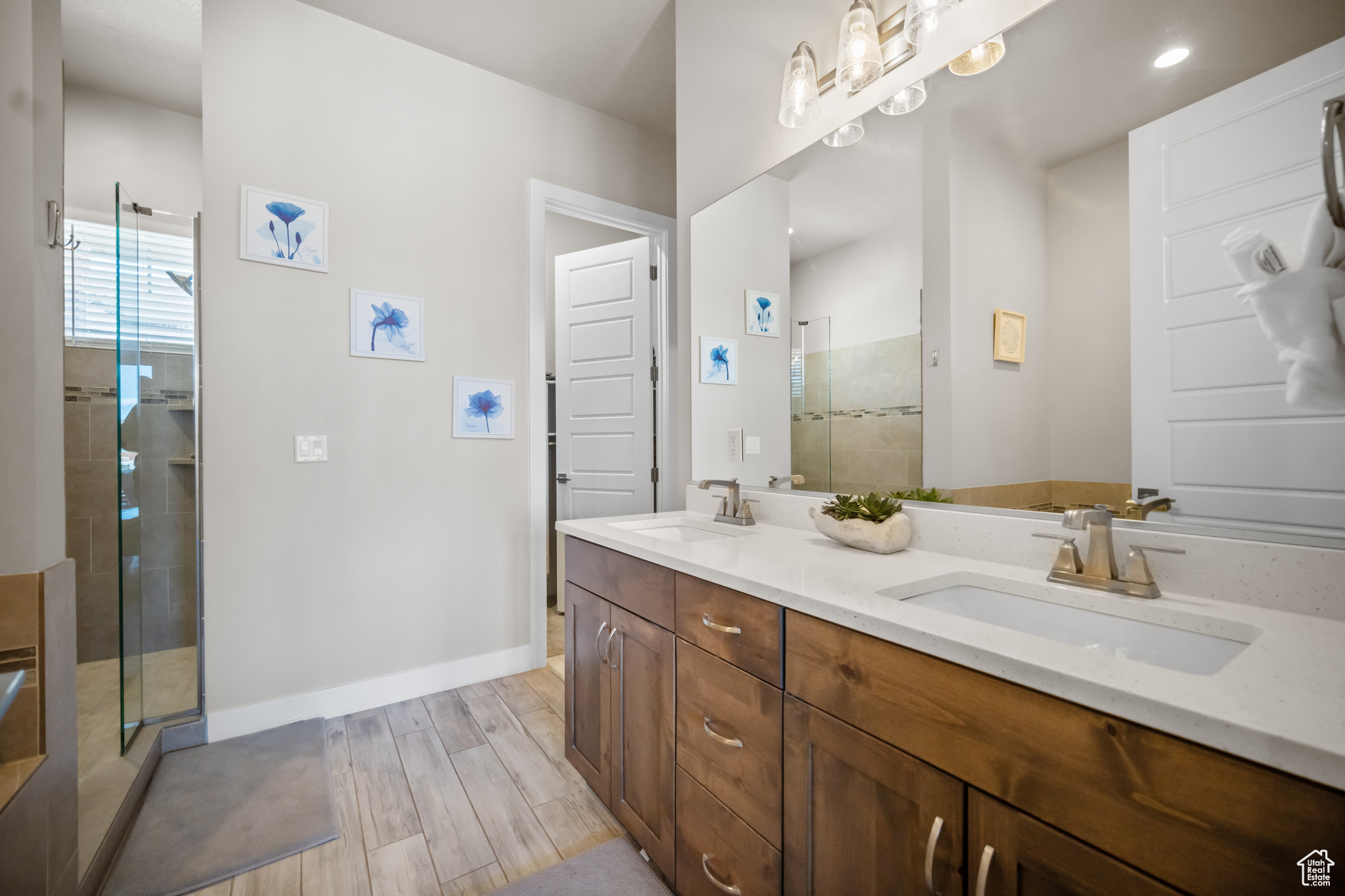 Bathroom featuring hardwood / wood-style flooring, a shower with shower door, and dual bowl vanity