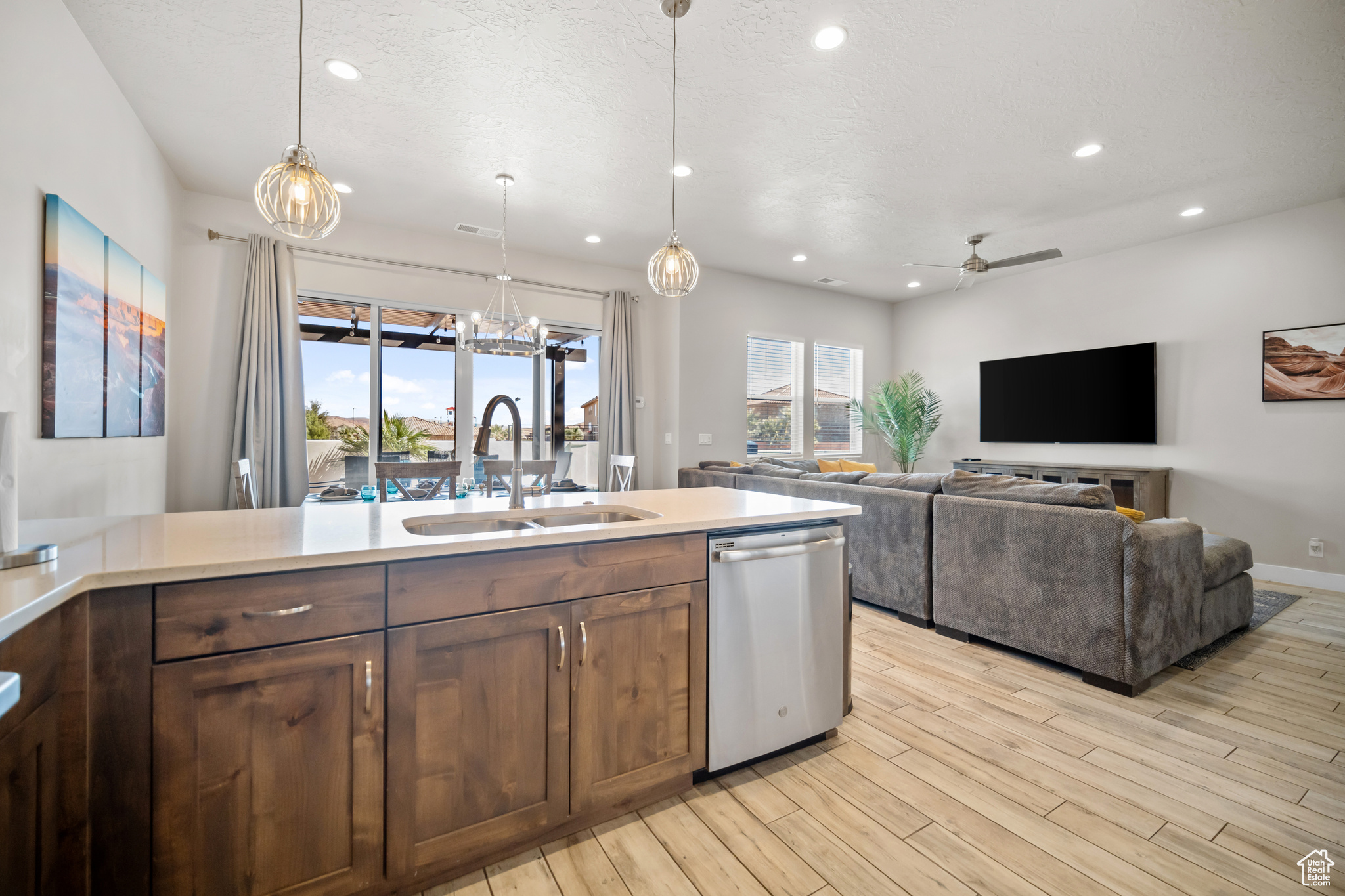 Kitchen with light wood-type flooring, ceiling fan, stainless steel dishwasher, pendant lighting, and sink