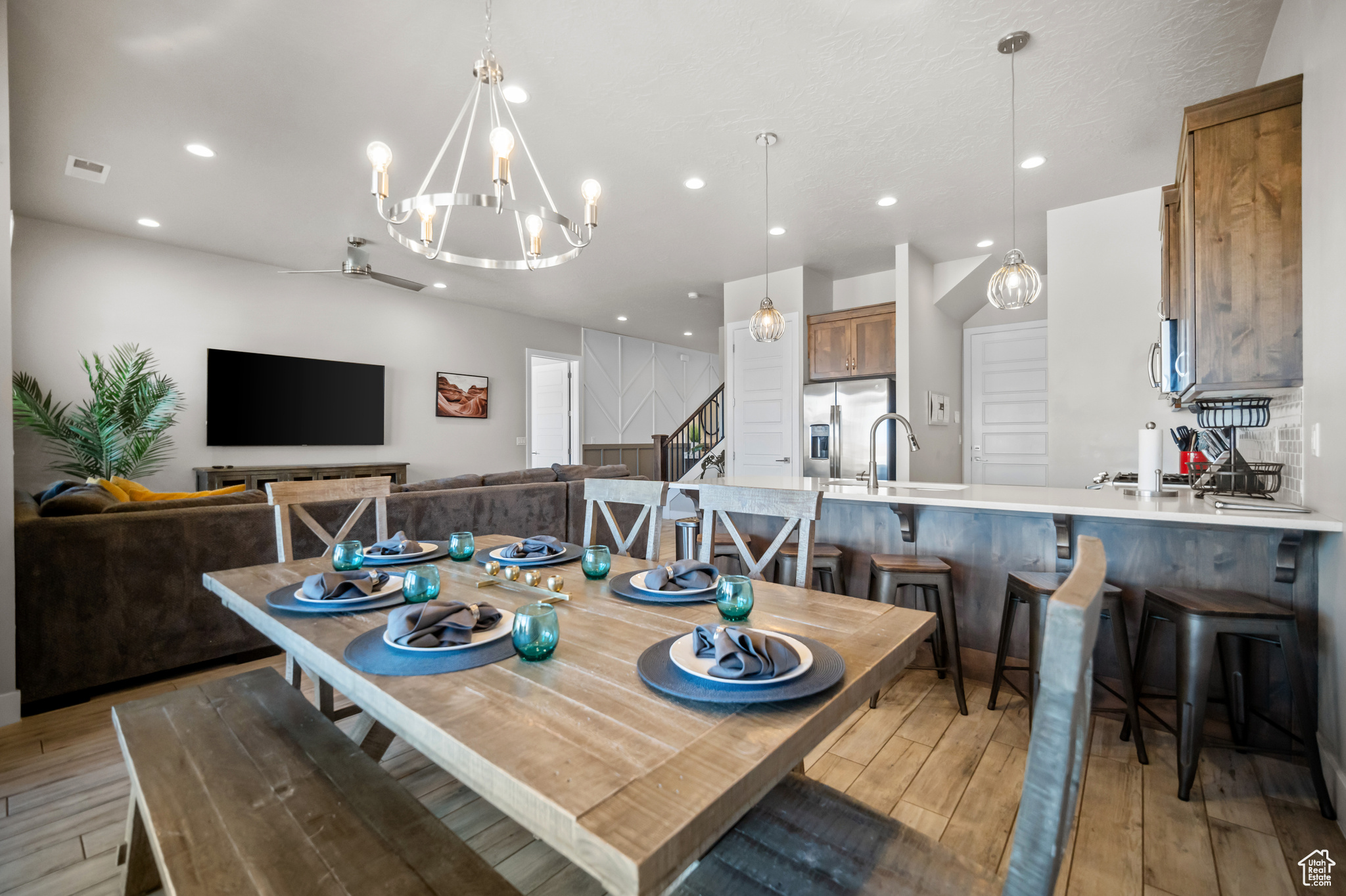 Dining room with sink, light wood-type flooring, and ceiling fan with notable chandelier