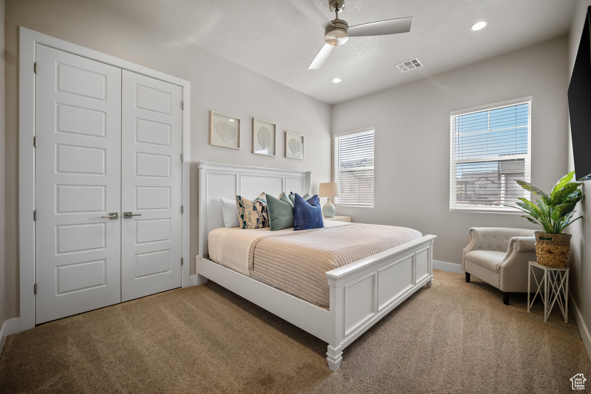 Bedroom with a closet, light colored carpet, and ceiling fan