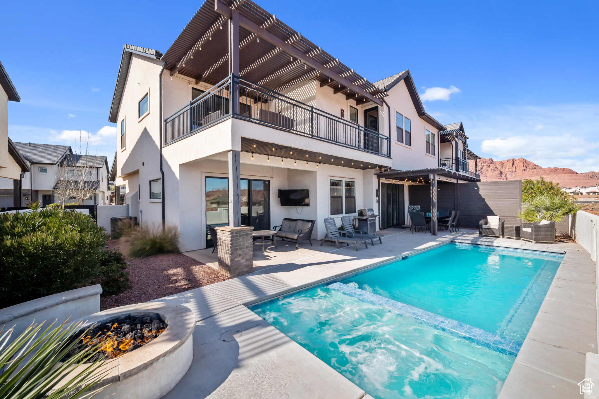 Back of house featuring a balcony, an outdoor hangout area, a fenced in pool, and a patio area