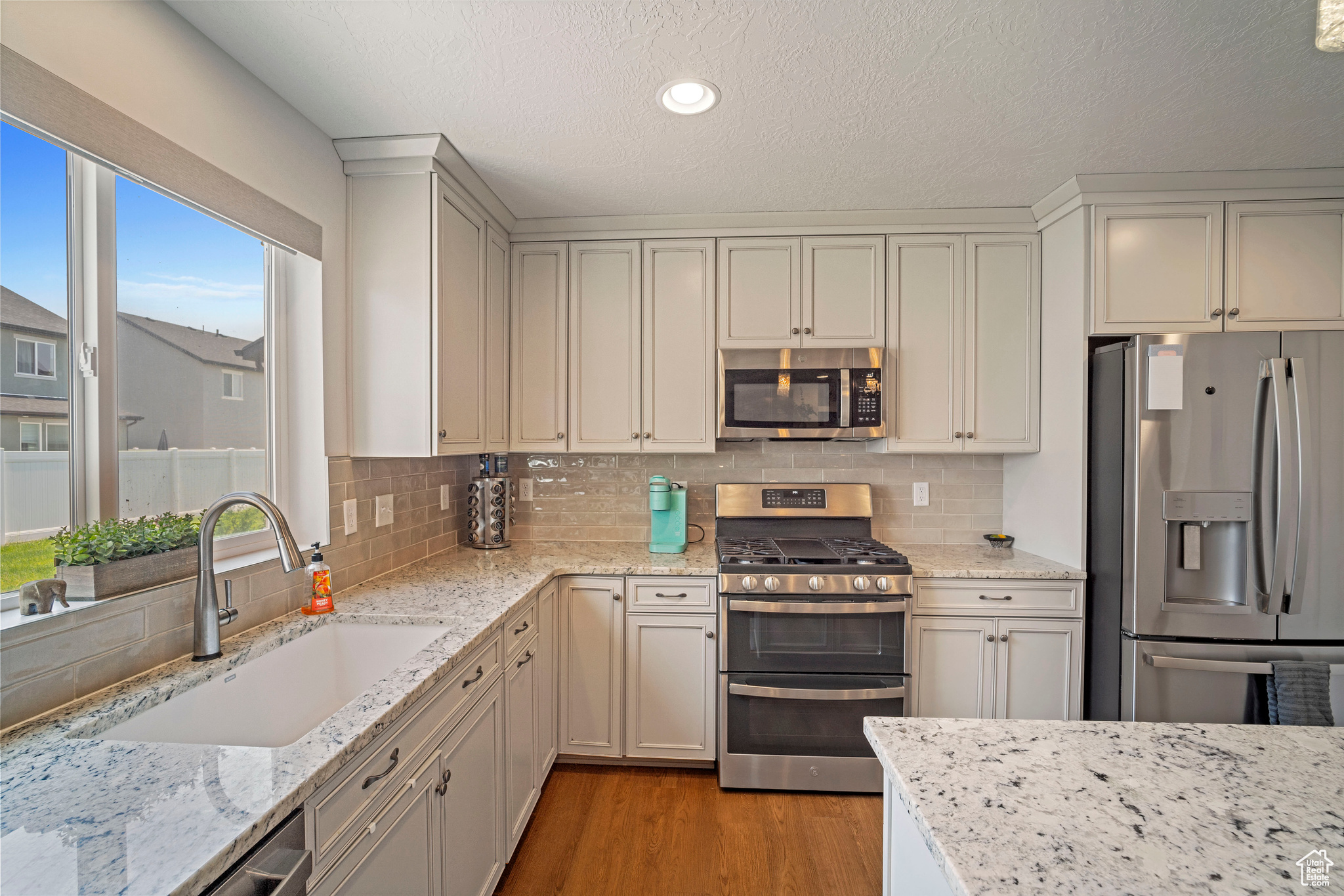 Kitchen with sink, light hardwood / wood-style flooring, appliances with stainless steel finishes, and a wealth of natural light