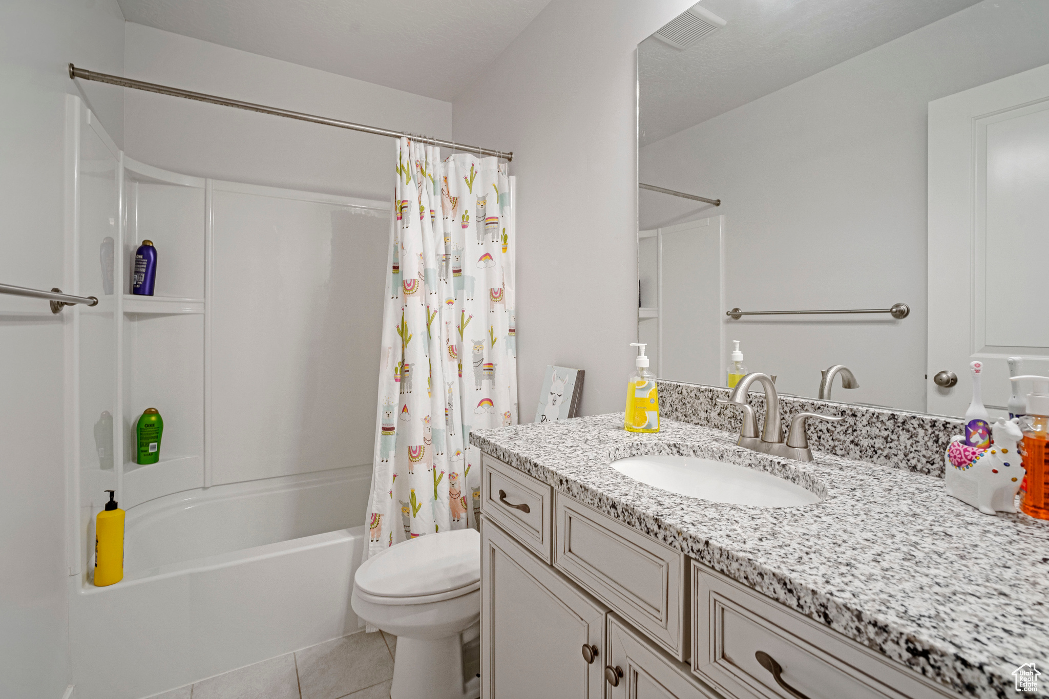 Full bathroom featuring vanity, shower / bath combo with shower curtain, tile patterned flooring, and toilet