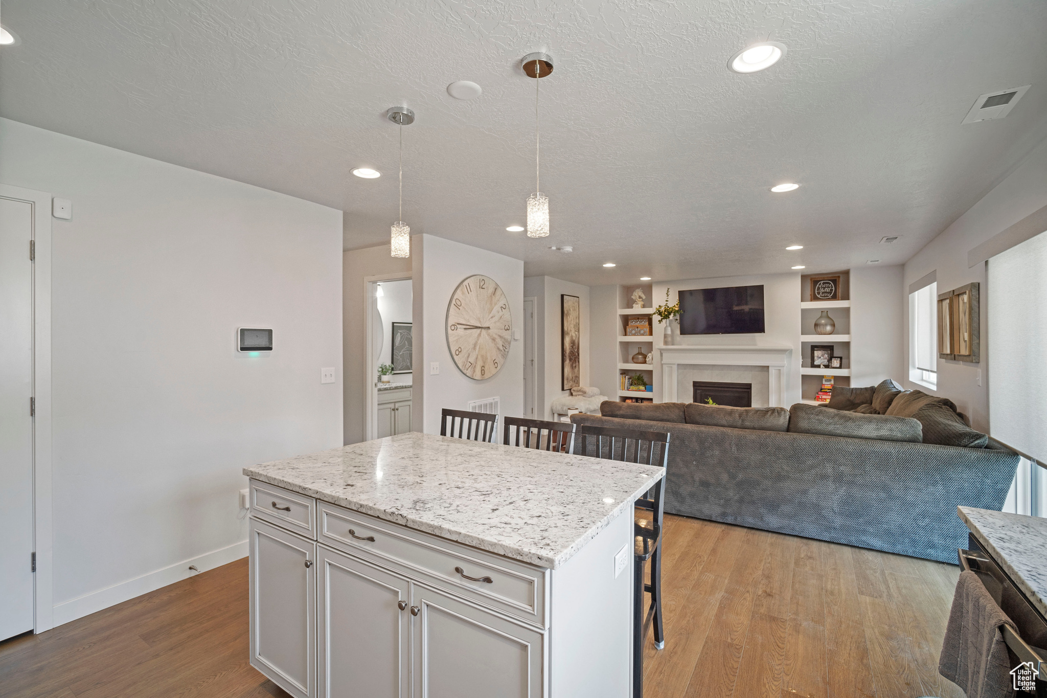 Kitchen featuring white cabinets, a breakfast bar, pendant lighting, light hardwood / wood-style floors, and a kitchen island