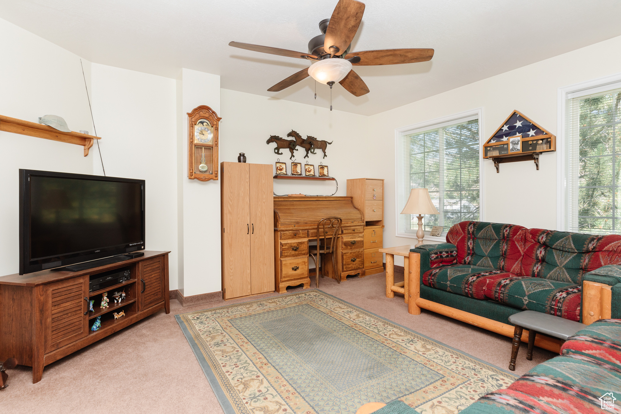 Carpeted living room with ceiling fan and a healthy amount of sunlight