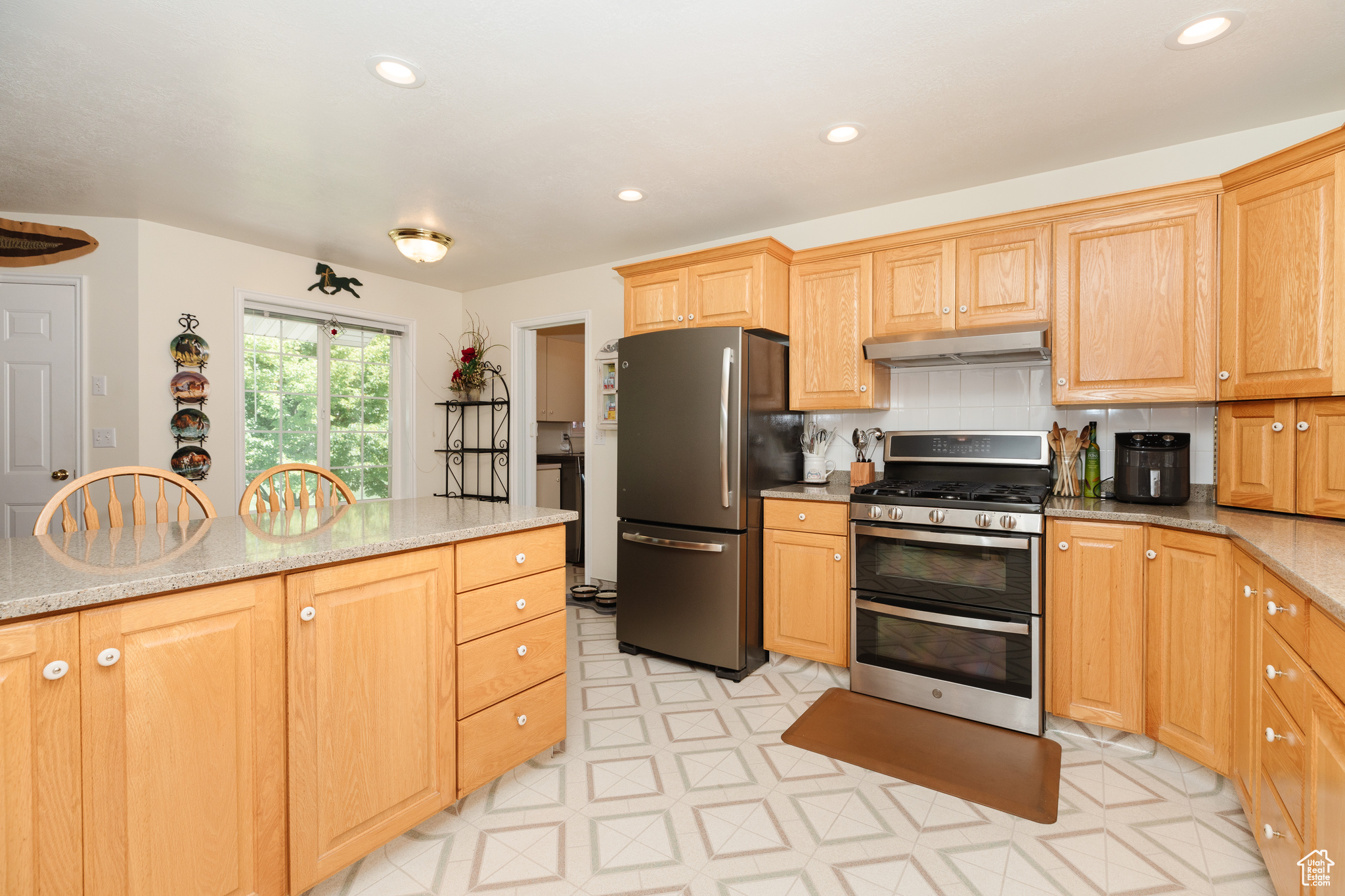 Kitchen featuring stainless steel appliances, backsplash, light stone counters, and light tile patterned floors