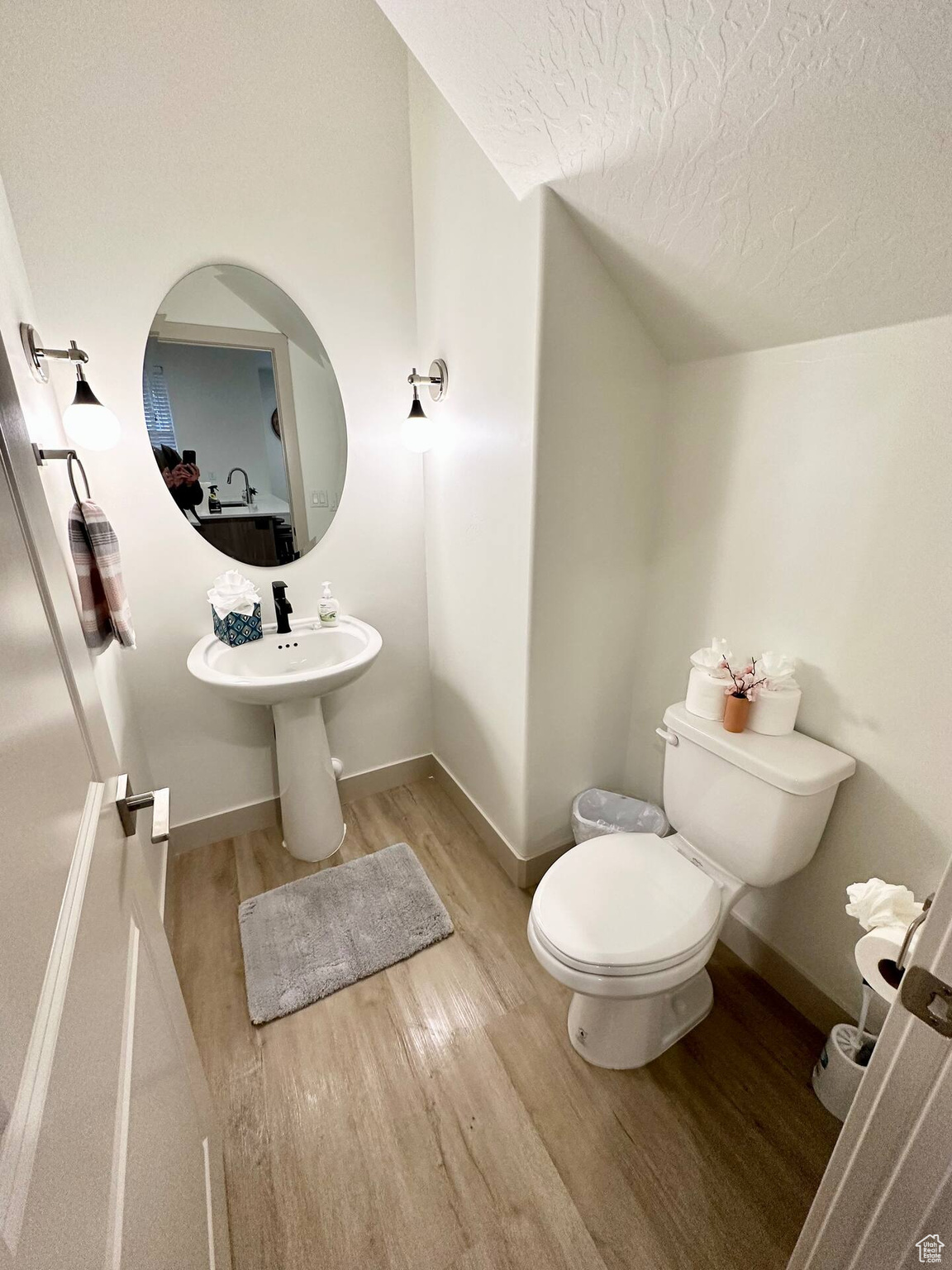 Bathroom with a textured ceiling, hardwood / wood-style flooring, and toilet