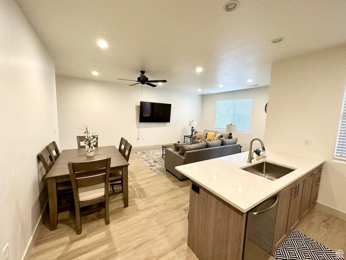 Kitchen featuring kitchen peninsula, sink, ceiling fan, and light wood-type flooring