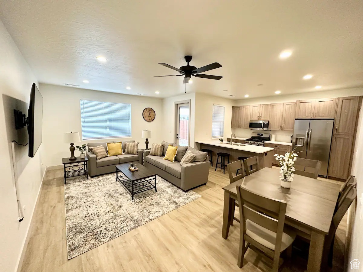 Living room featuring ceiling fan, sink, and light hardwood / wood-style flooring