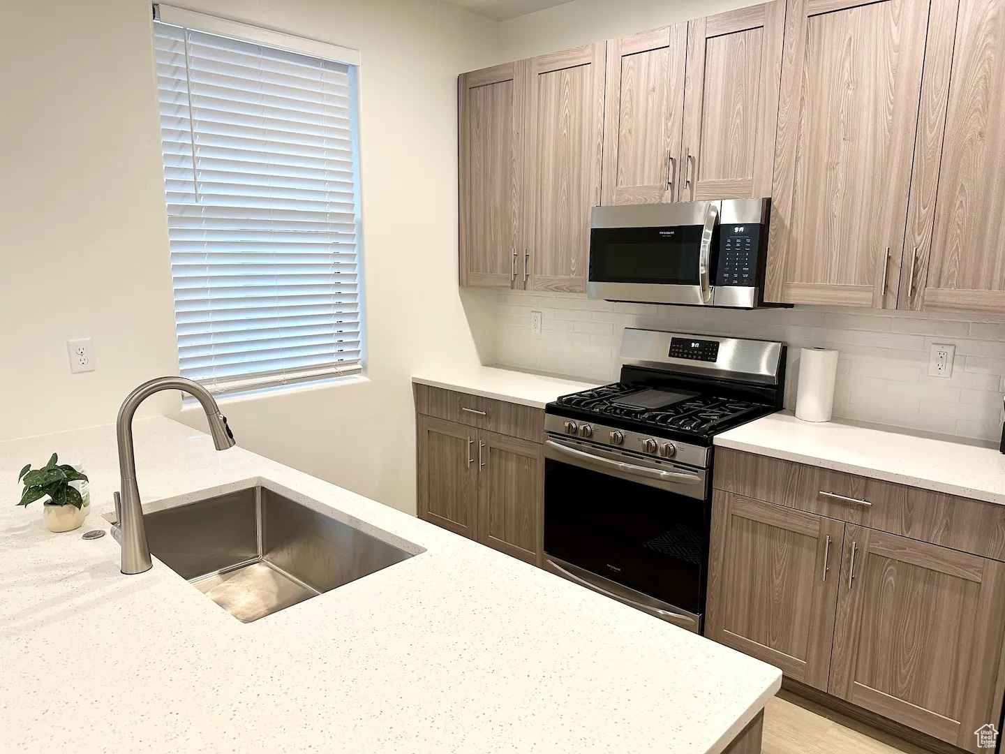 Kitchen with decorative backsplash, appliances with stainless steel finishes, and sink