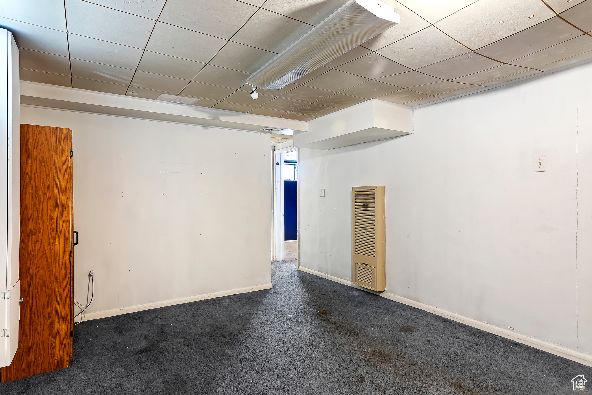 Empty room featuring a drop ceiling and carpet flooring